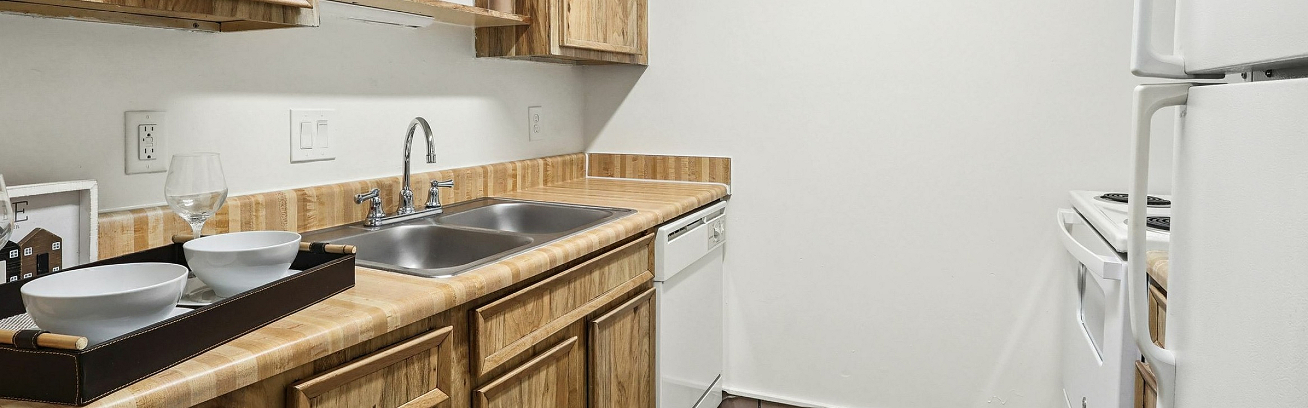 Charming apartment kitchen with rustic wooden cabinets, modern appliances, and elegant tile flooring.