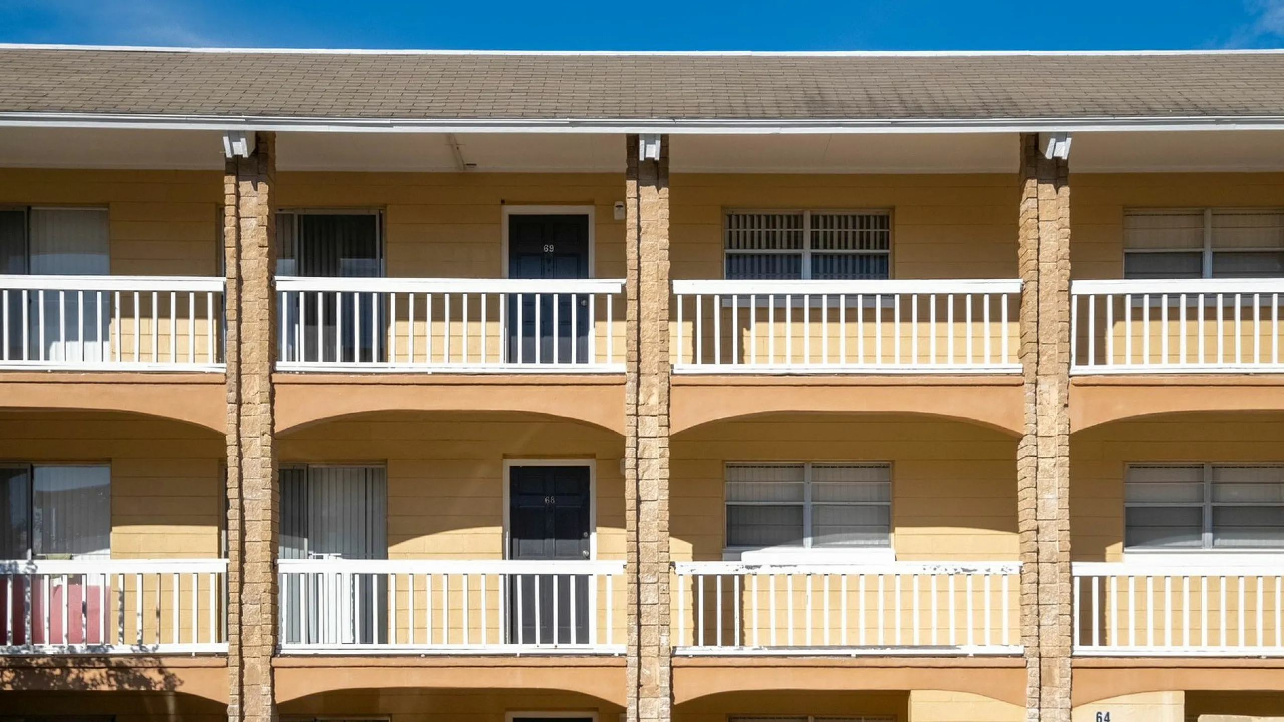Charming two-story apartment building with sunny yellow exterior and inviting balconies, ideal for modern living.