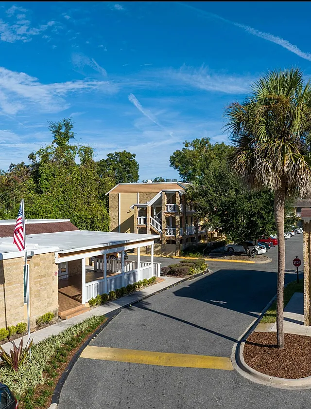 Inviting apartment complex with palm trees, vibrant greenery, and well-maintained landscaping under a sunny blue sky.