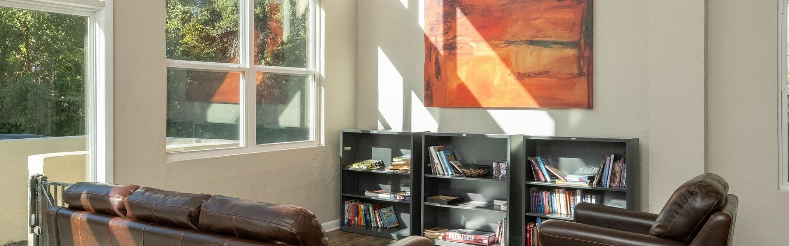 Bright and inviting living room with high ceilings, leather sofas, and large windows offering lush garden views.