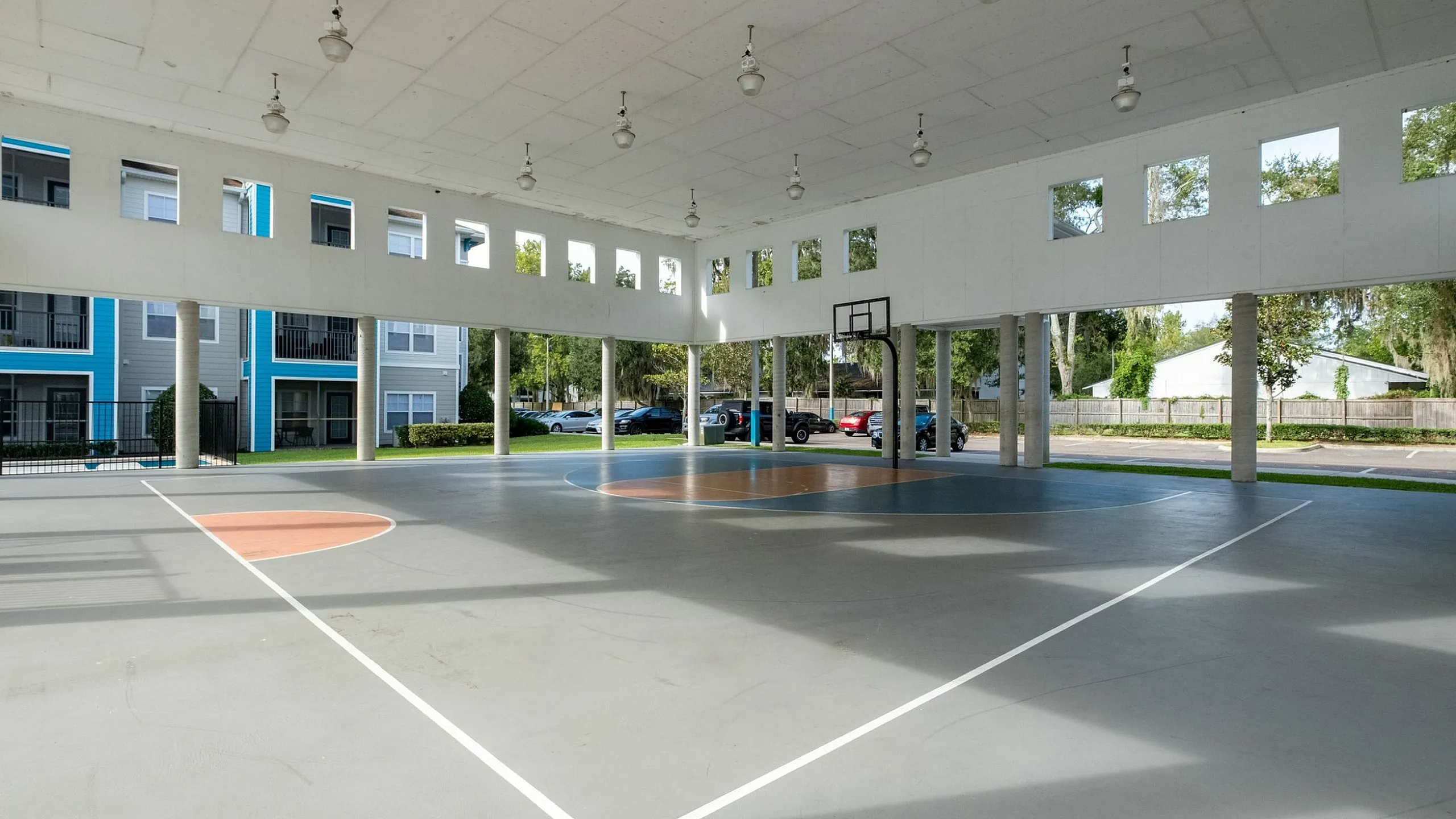 Spacious indoor basketball court with high ceilings and abundant natural light, perfect for sports enthusiasts.