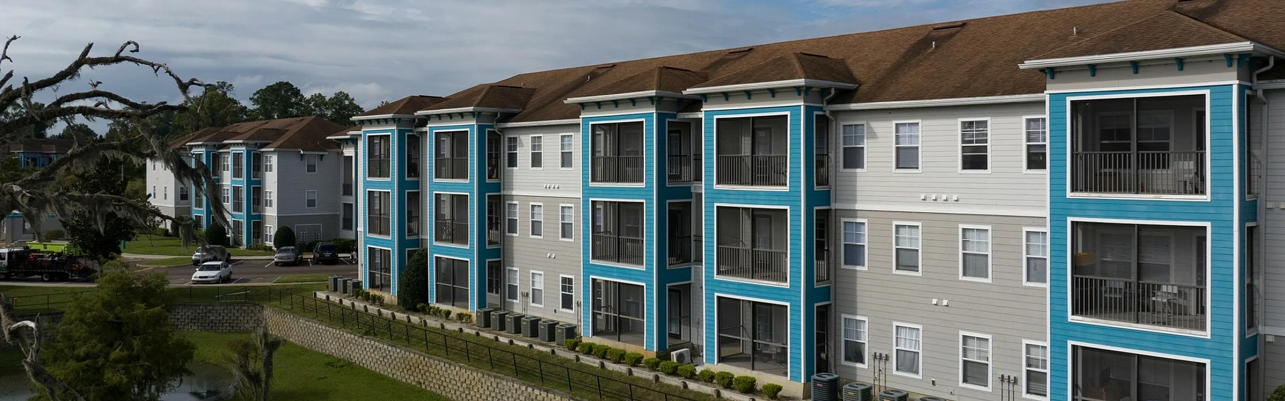 Modern apartment complex featuring stylish balconies and lush green surroundings under a vibrant sky.