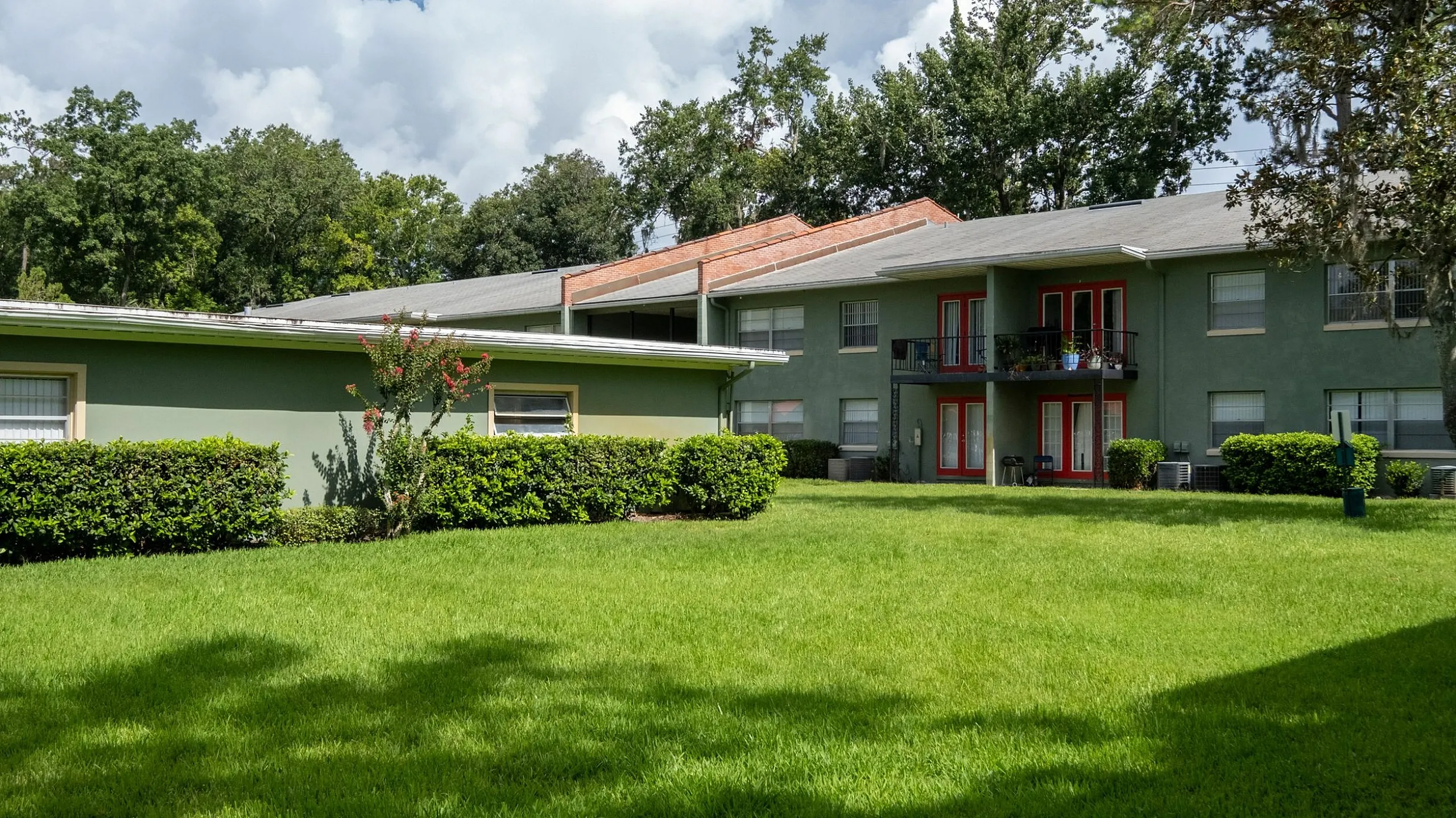 Charming apartment complex with lush green lawns, vibrant foliage, and spacious outdoor areas for relaxation.