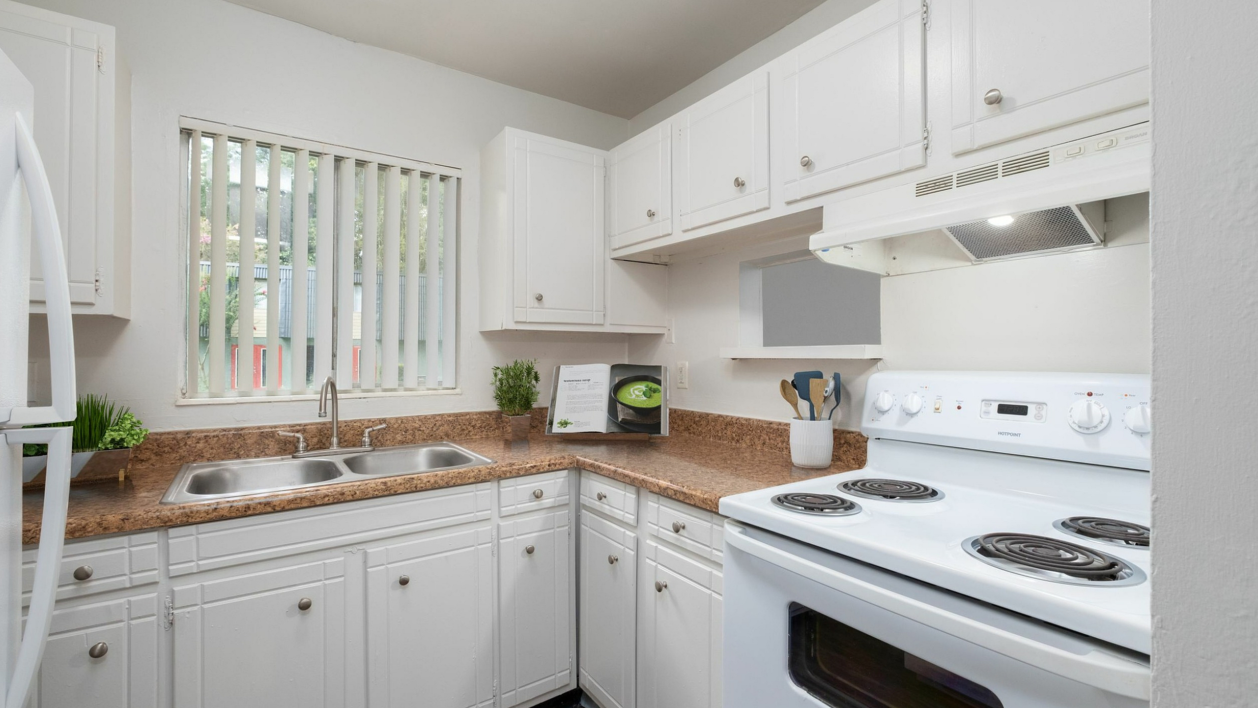 Bright modern kitchen with white cabinetry, sleek countertops, and large window for natural light.