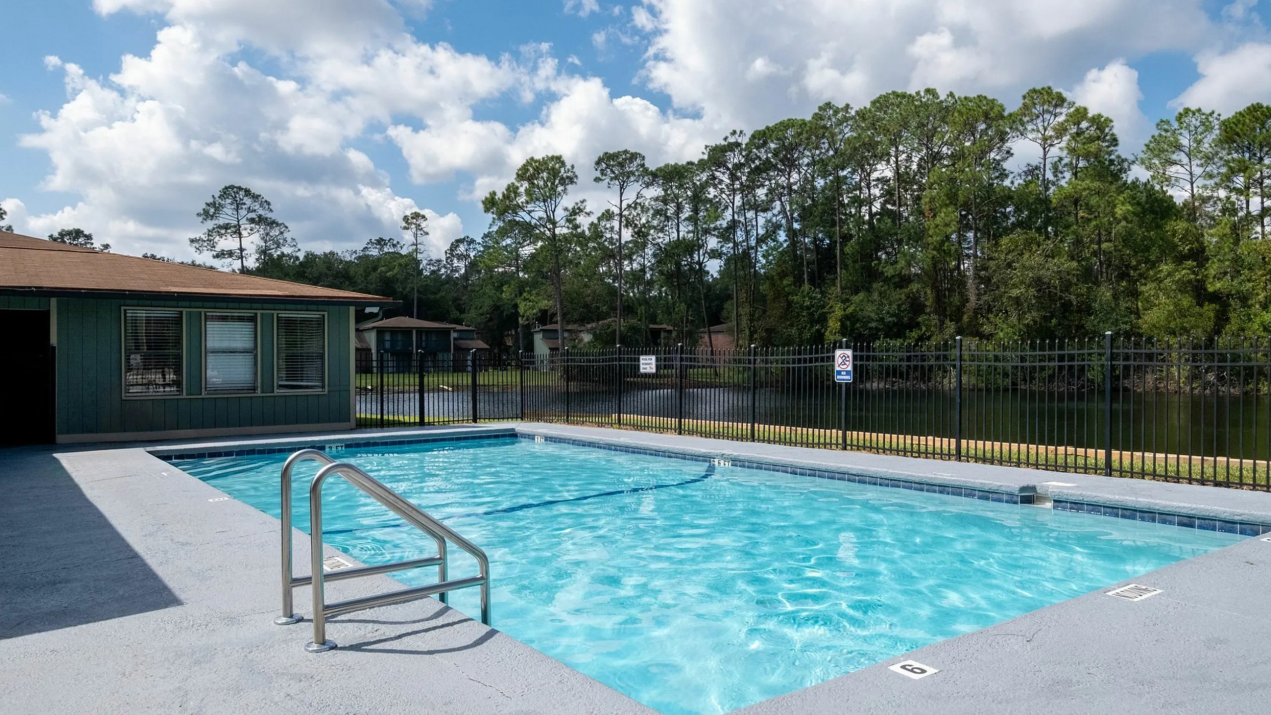 Inviting community swimming pool with serene forest view, perfect for relaxation and leisure.