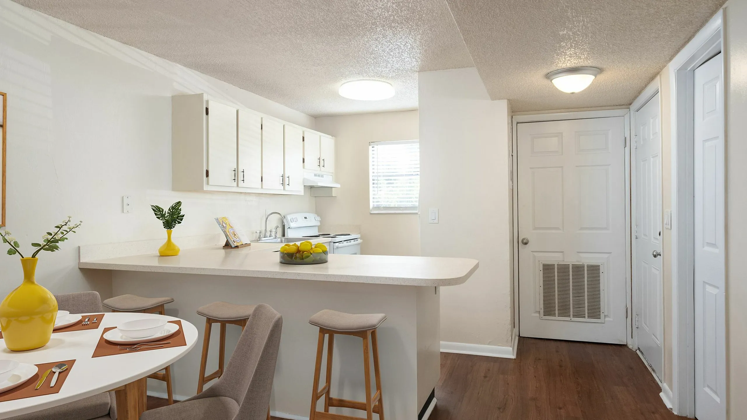 Charming kitchen with sleek countertops, stylish stools, and bright dining area featuring elegant table settings and decor accents.
