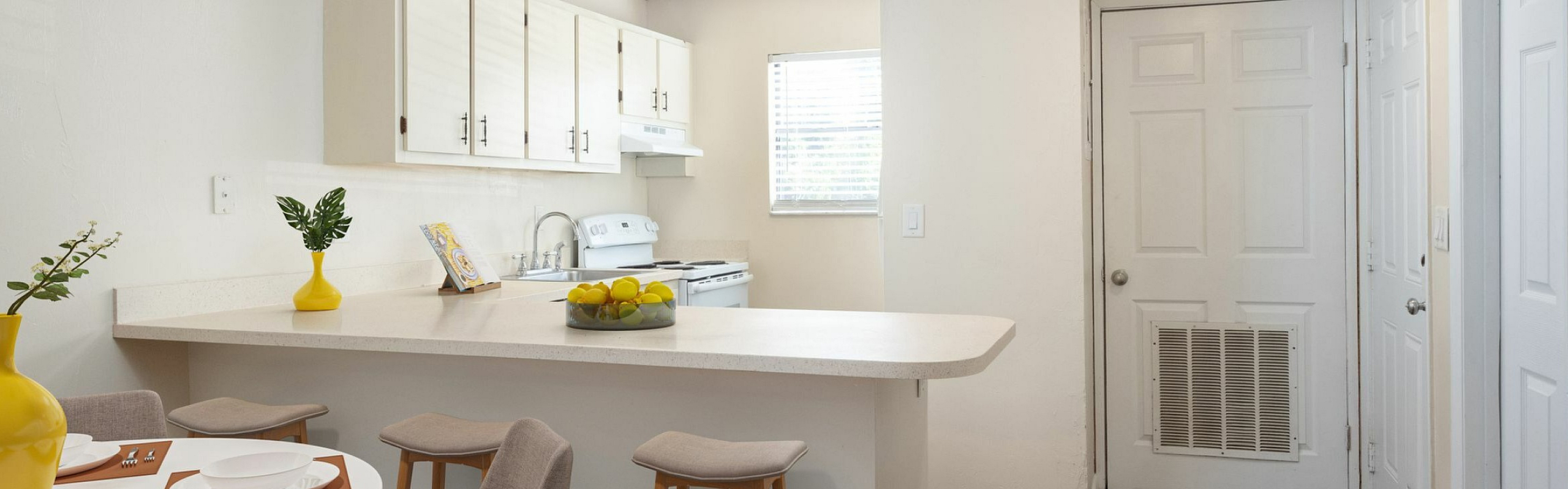 Inviting modern kitchen with white cabinets, cozy dining area, and stylish bar stools, perfect for entertaining.
