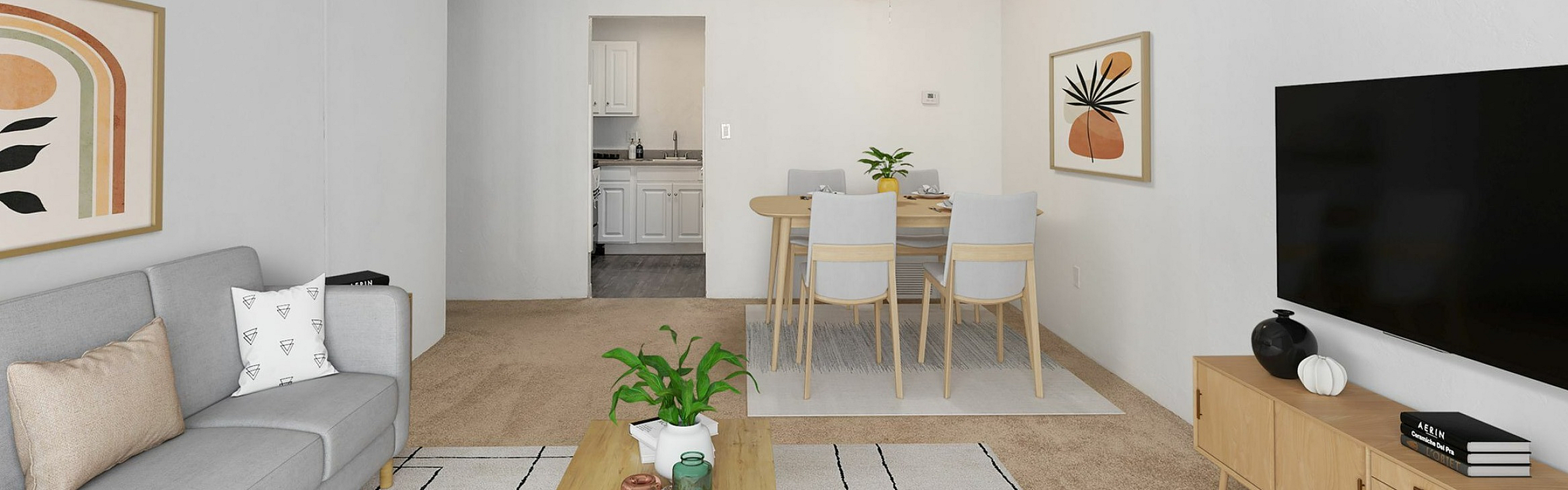 Modern living room with elegant decor, featuring a gray sofa, stylish artwork, and a flat-screen TV, seamlessly connected to a dining area and kitchen.