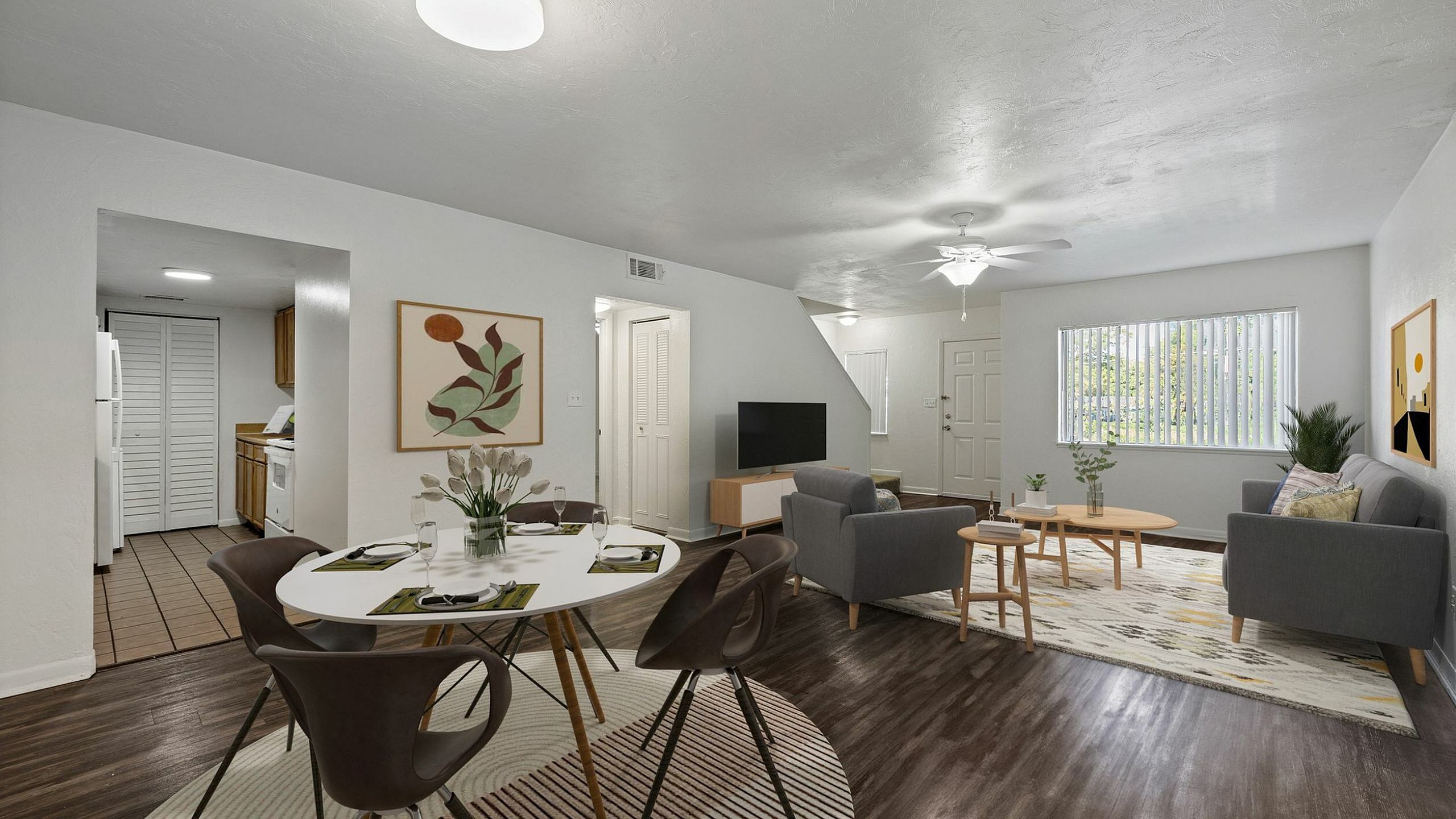 Modern open-concept living room with stylish gray sofas, a cozy dining area, and elegant decor, perfect for entertaining.