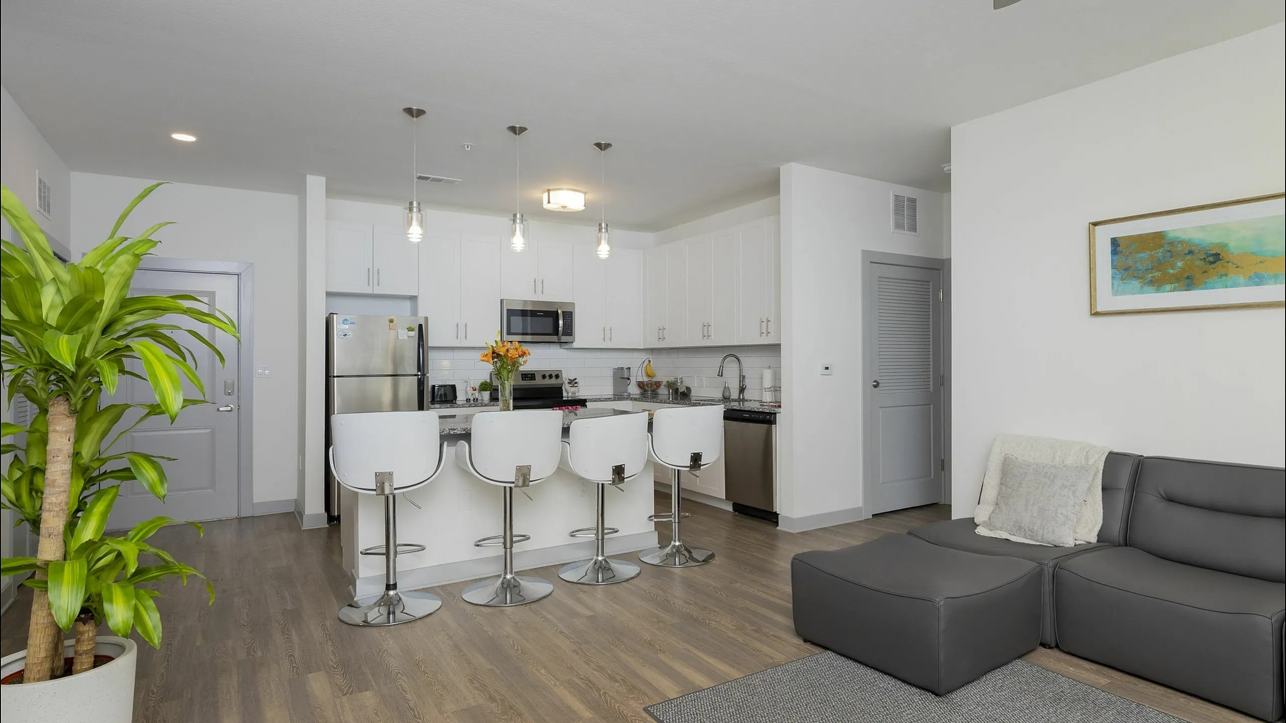 Modern open-concept living space featuring a sleek kitchen with stainless steel appliances, elegant bar seating, and a cozy lounge area with stylish decor.