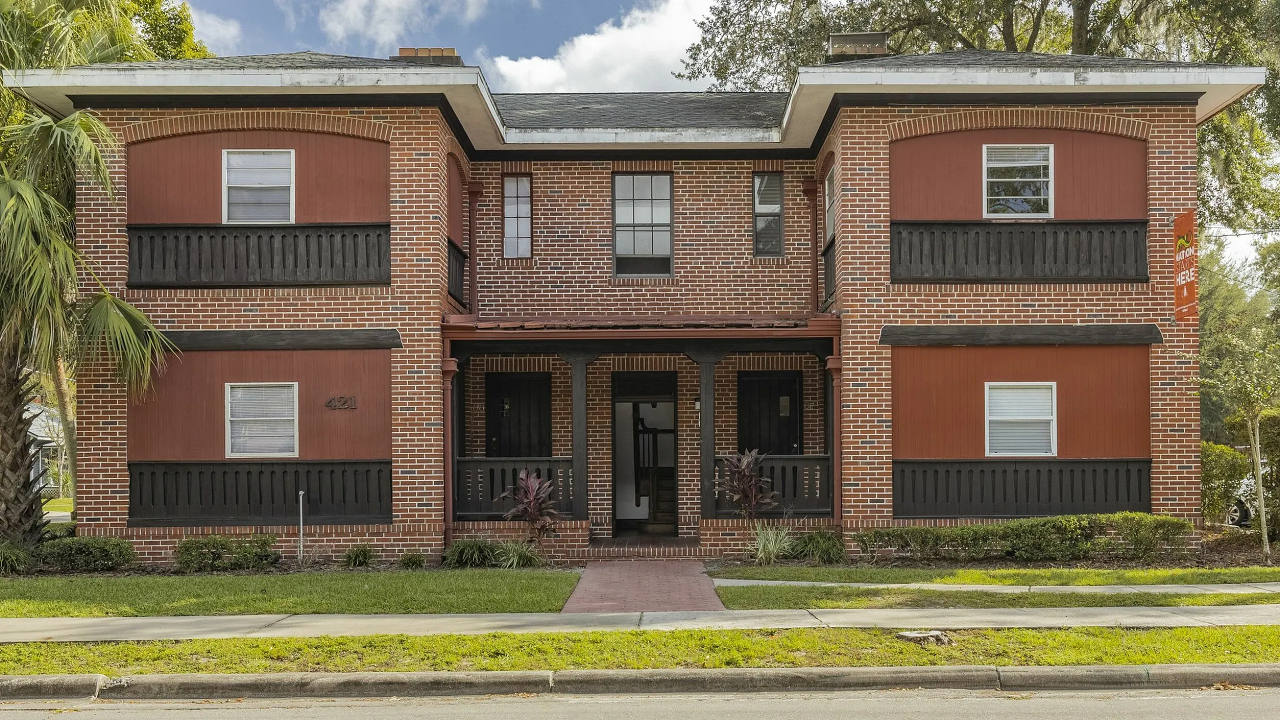 Charming brick apartment building with classic architectural style and lush greenery, offering inviting suburban living.