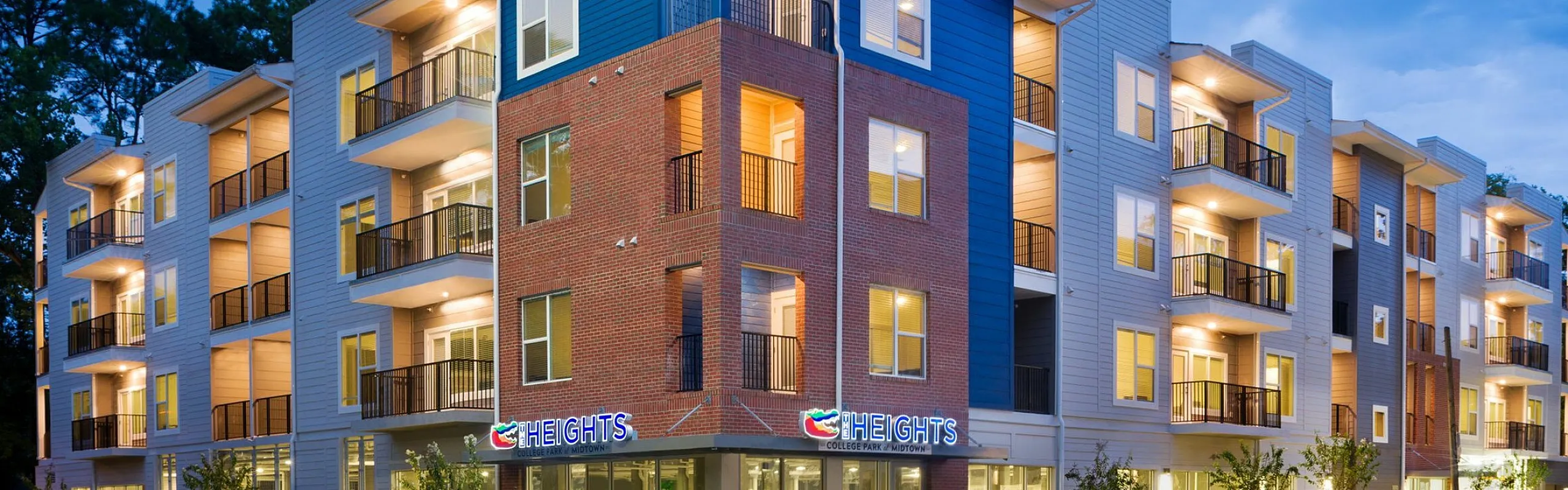Modern apartment building with stylish balconies and vibrant exterior lighting, ideal for urban living.