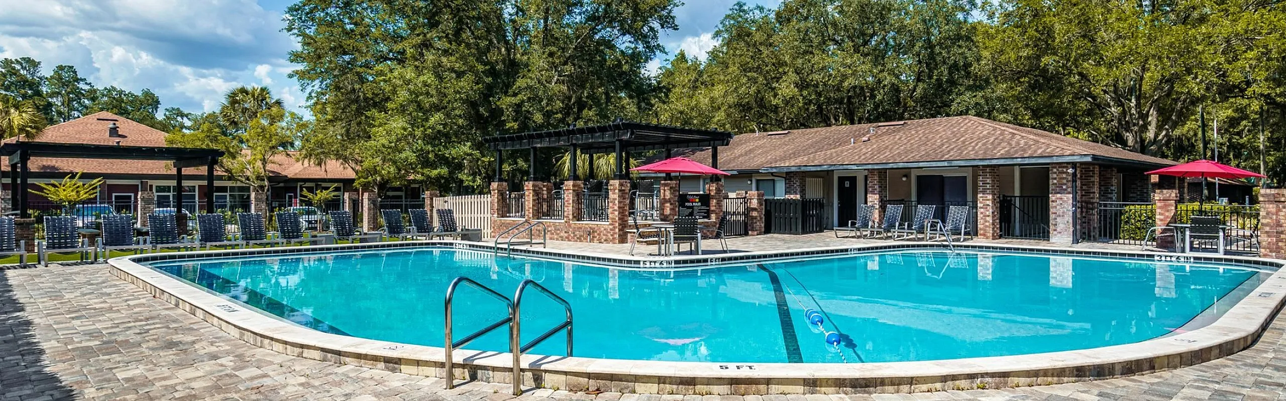 Inviting outdoor pool area surrounded by lush greenery and comfortable lounge chairs, perfect for relaxation and enjoyment.