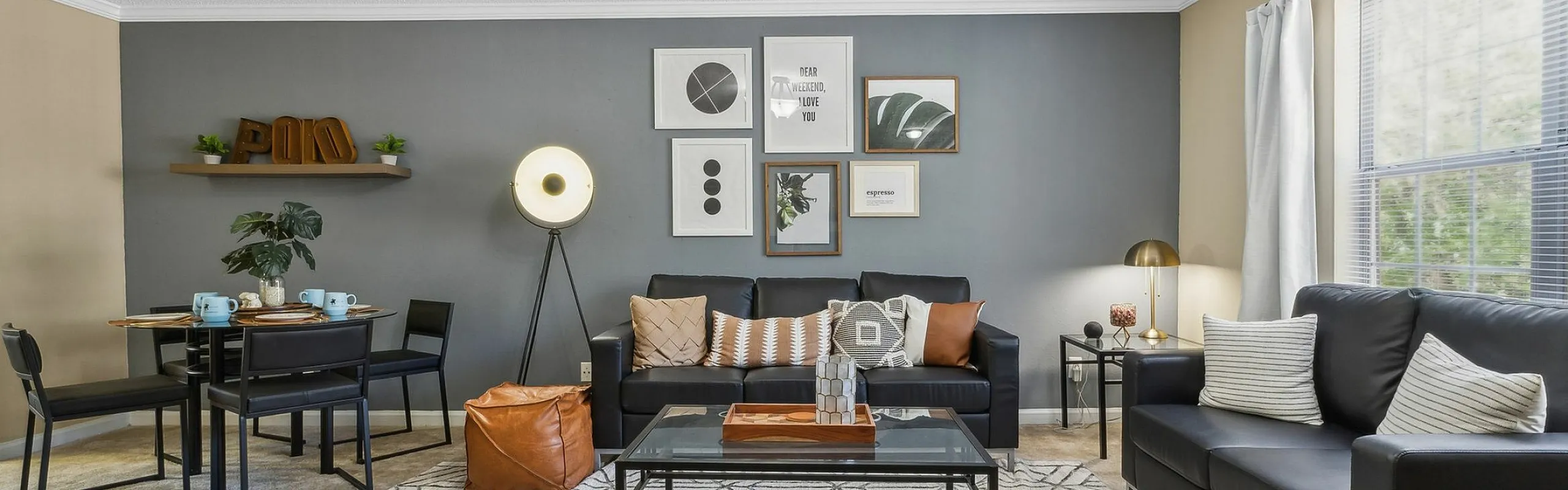 Modern living room with stylish black sofas, geometric rug, and chic gallery wall art, illuminated by natural light from a large window.