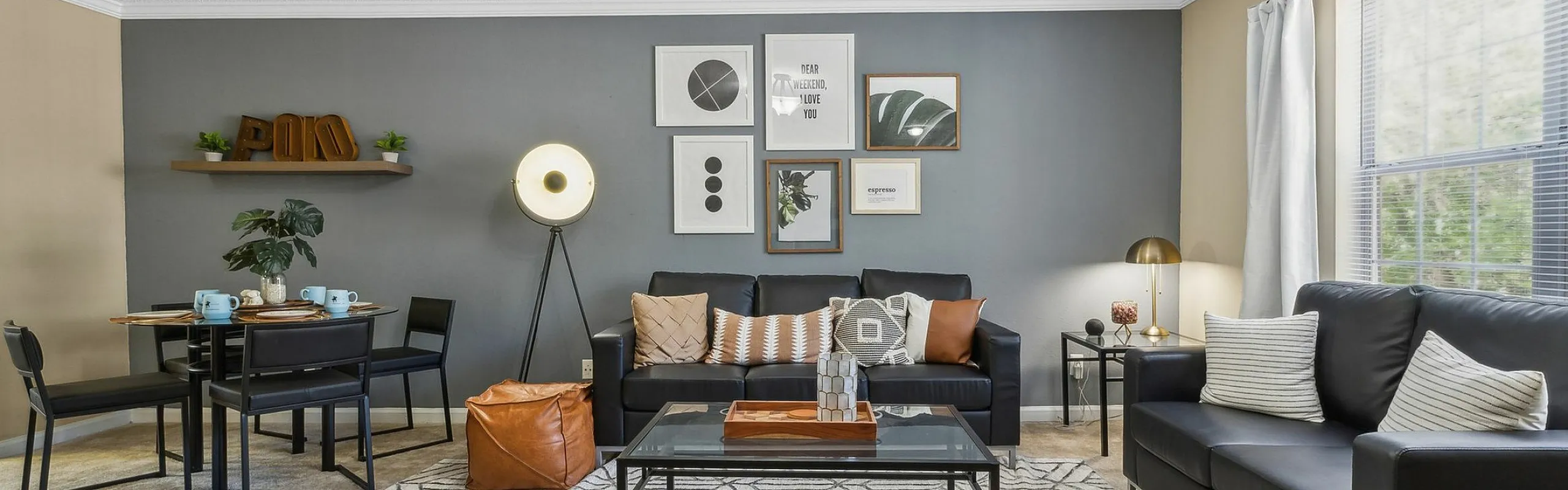 Contemporary living room with elegant decor, featuring a stylish black leather sofa, modern art pieces, and abundant natural light.