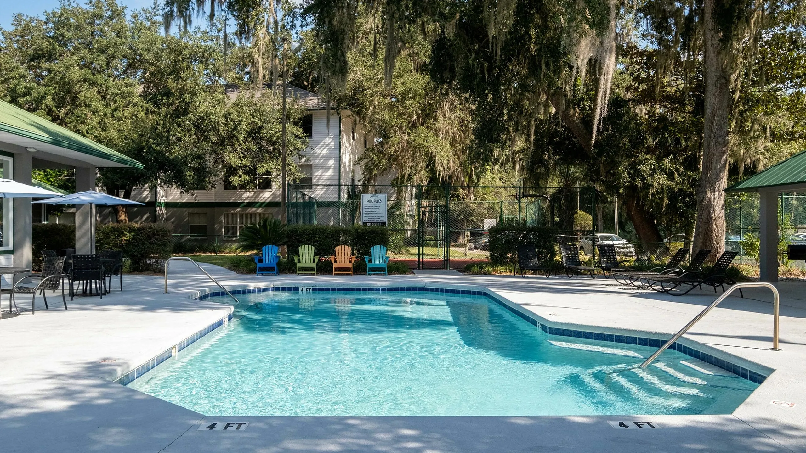 Inviting outdoor pool area surrounded by lush greenery and comfortable seating, perfect for relaxation and leisure.