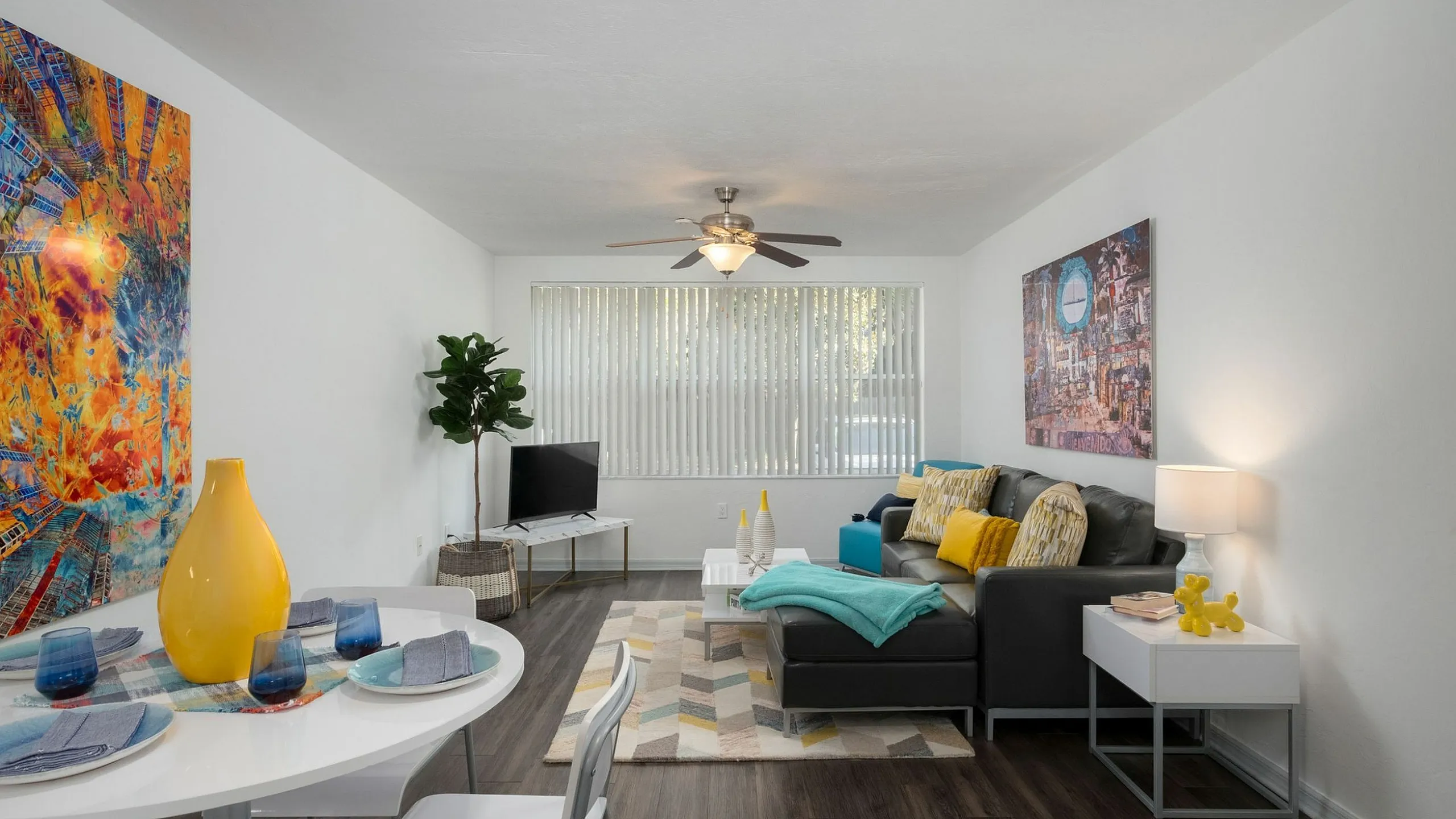 Modern living room with vibrant artwork, cozy seating area, and stylish dining setup, accented by bright decor and natural light.