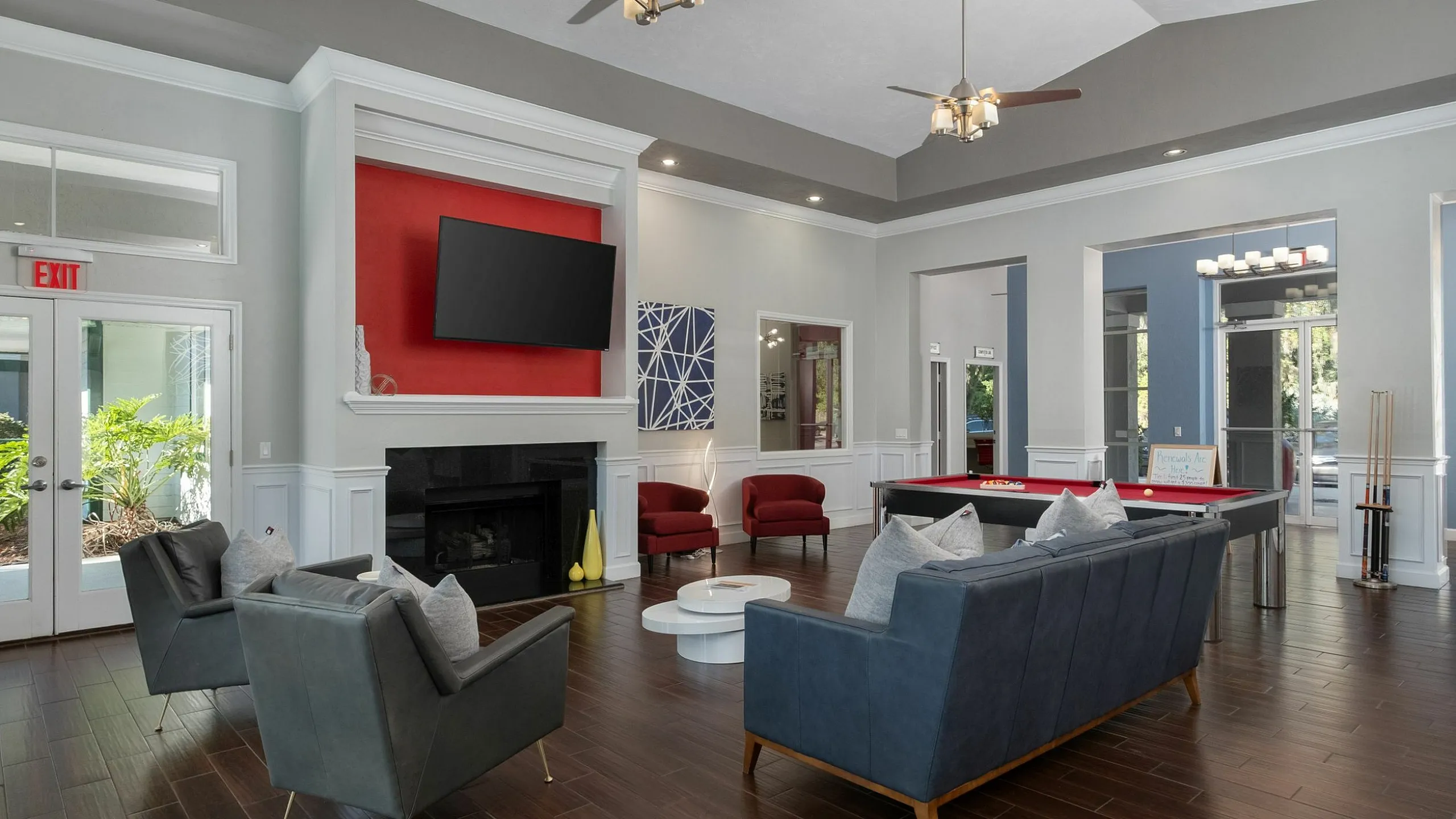 Elegant community lounge showcasing modern furniture, a wall-mounted TV, and a chic pool table under sophisticated lighting.