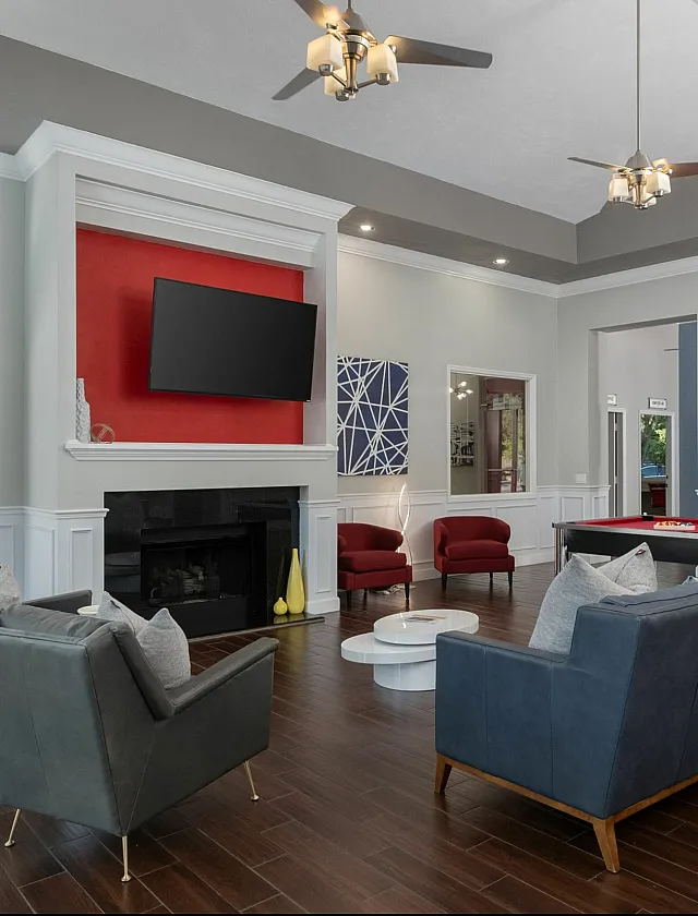 Elegant communal lounge area featuring modern seating, a vibrant red accent wall, flat-screen TV, and a stylish pool table, ideal for social gatherings and relaxation.