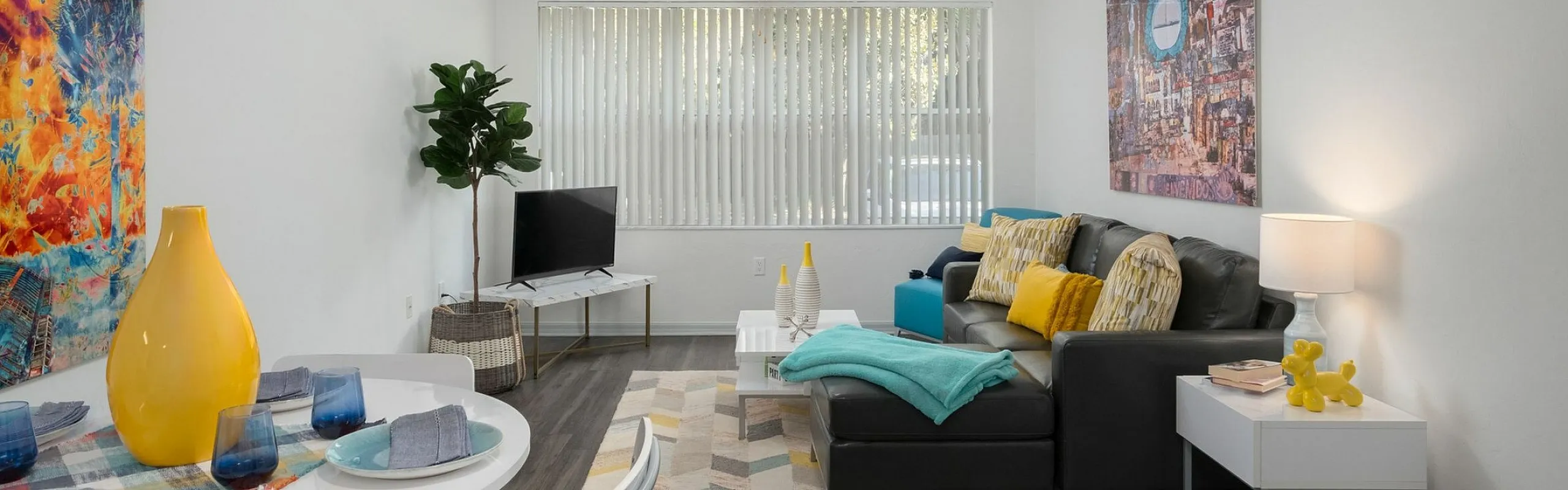 Inviting living room with modern decor, featuring a stylish sofa, vibrant artwork, and a cozy dining area with a splash of color.