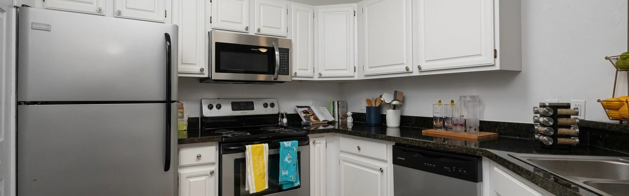Modern kitchen with sleek stainless steel appliances, white cabinetry, and dark granite countertops, offering a bright and inviting cooking space.
