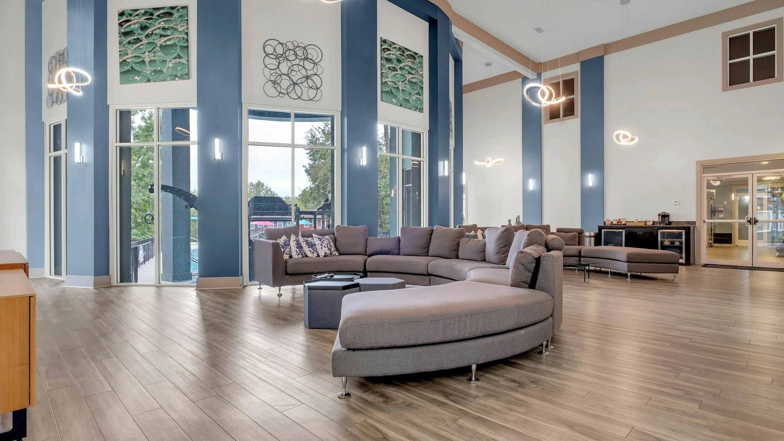 Luxurious and spacious living area with modern decor, large windows, stylish lighting, and a comfortable sectional sofa.