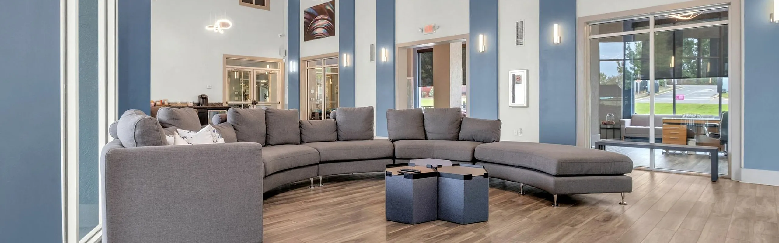 Elegant apartment community lounge featuring a modern sectional sofa, stylish lighting, and inviting wood flooring.