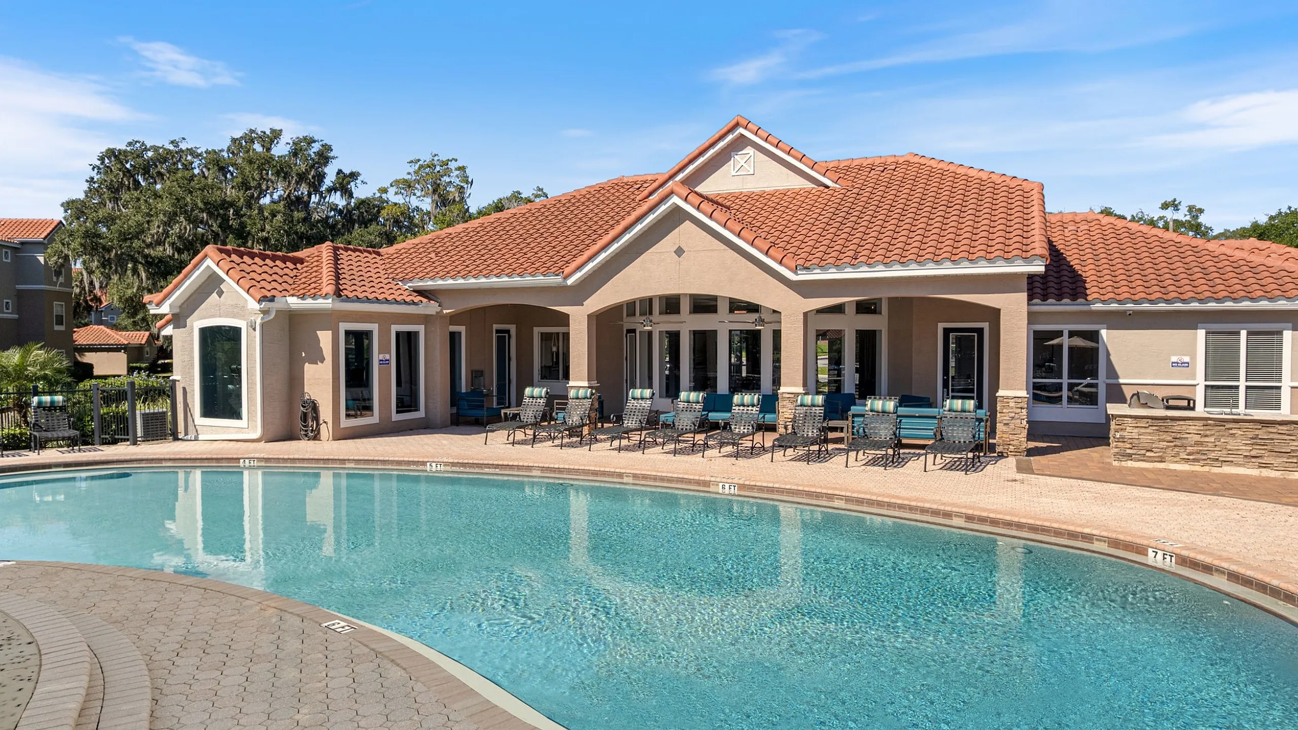 Elegant apartment retreat with a pristine outdoor pool, surrounded by chic sun loungers and lush greenery, perfect for relaxation and leisure.