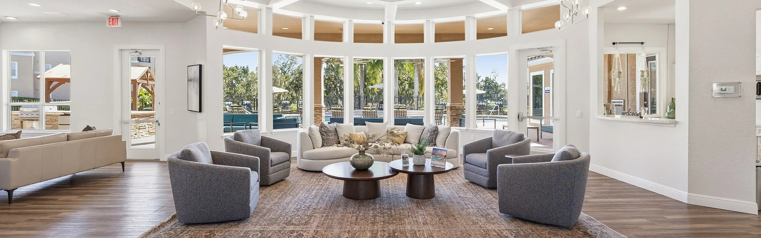Elegant and spacious living area with modern furniture, large windows offering scenic outdoor views, and a sleek wooden floor.