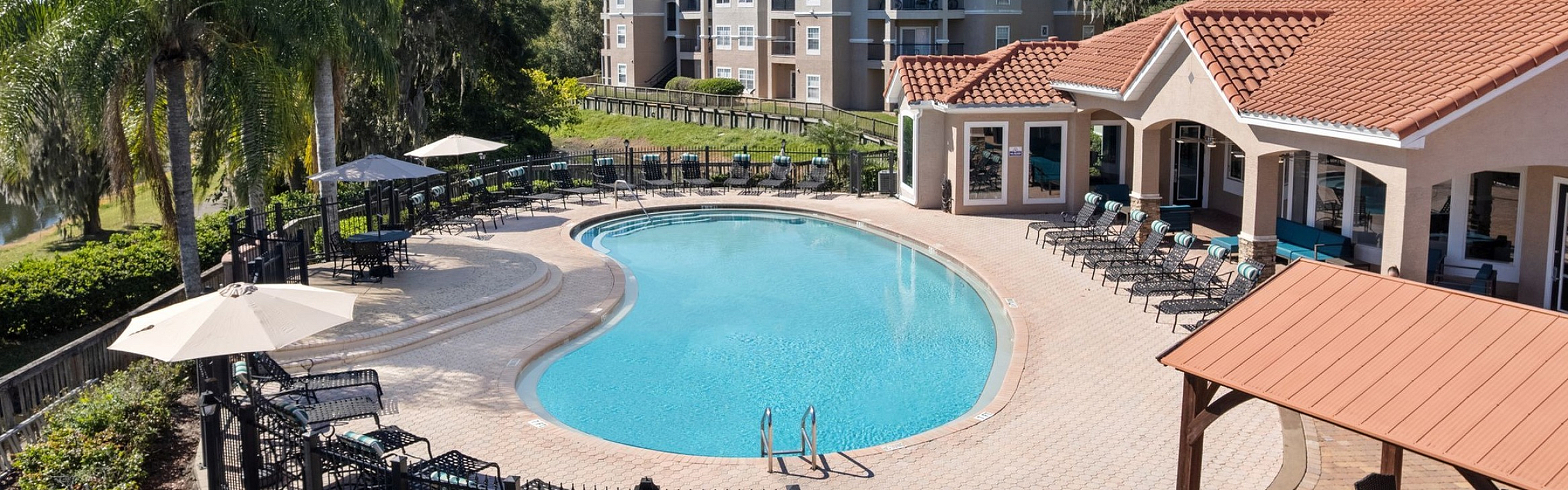 Luxurious apartment complex with a stunning resort-style pool, surrounded by lush greenery and elegant architecture.
