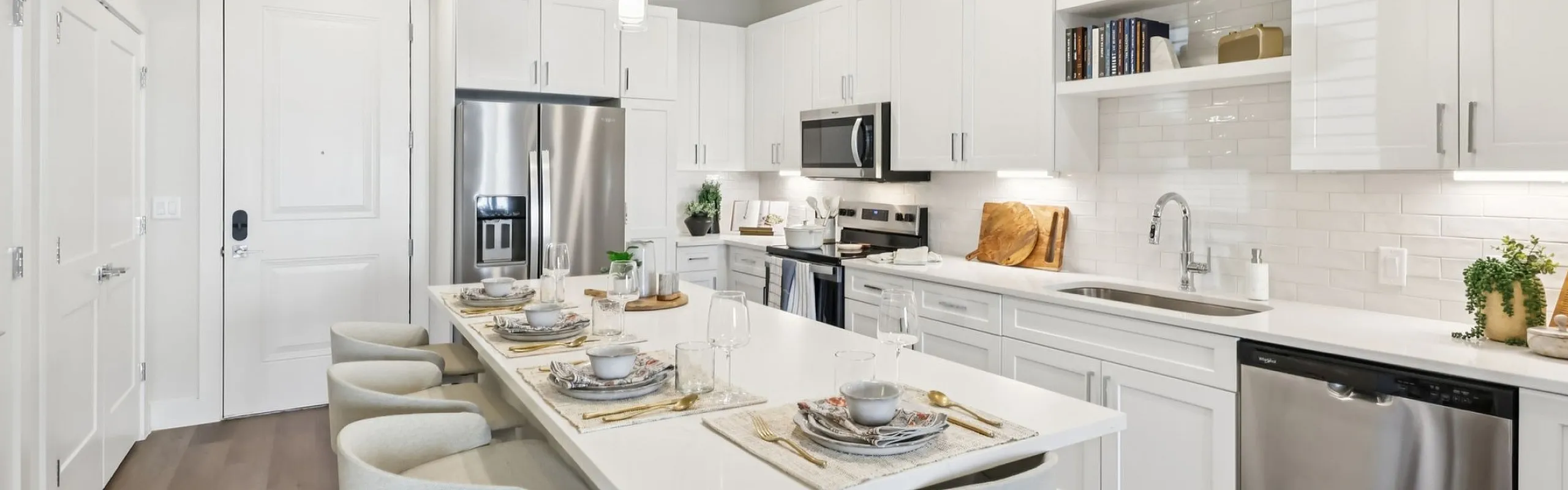 Luxurious modern kitchen with sleek white cabinetry, stainless steel appliances, and a stylish breakfast bar set for dining.