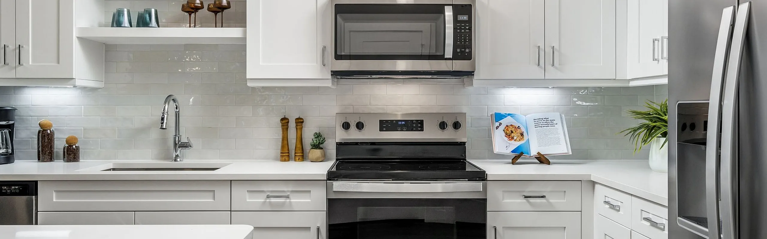 Modern kitchen with sleek white cabinetry, stainless steel appliances, and elegant open shelving.