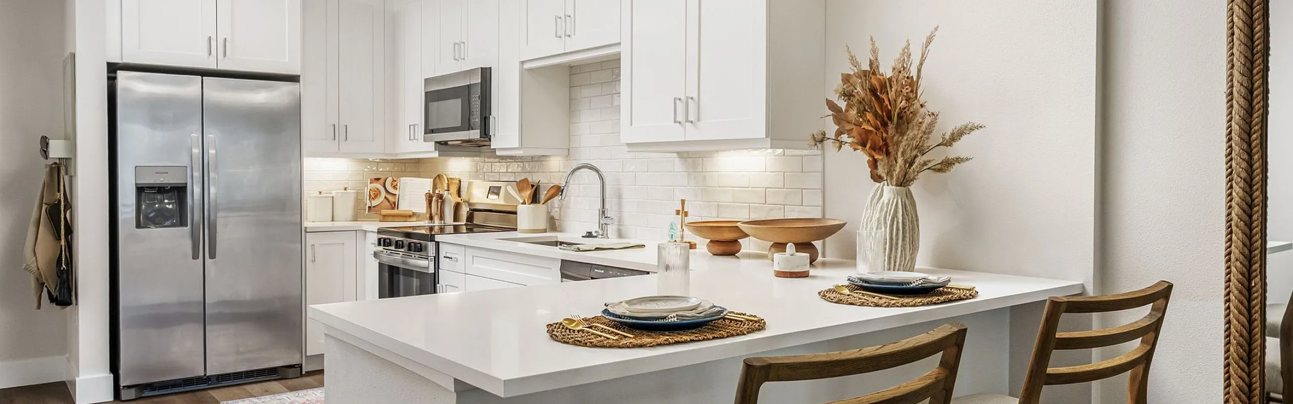 Modern kitchen with sleek white cabinetry, stainless steel appliances, and a stylish breakfast bar set for two.