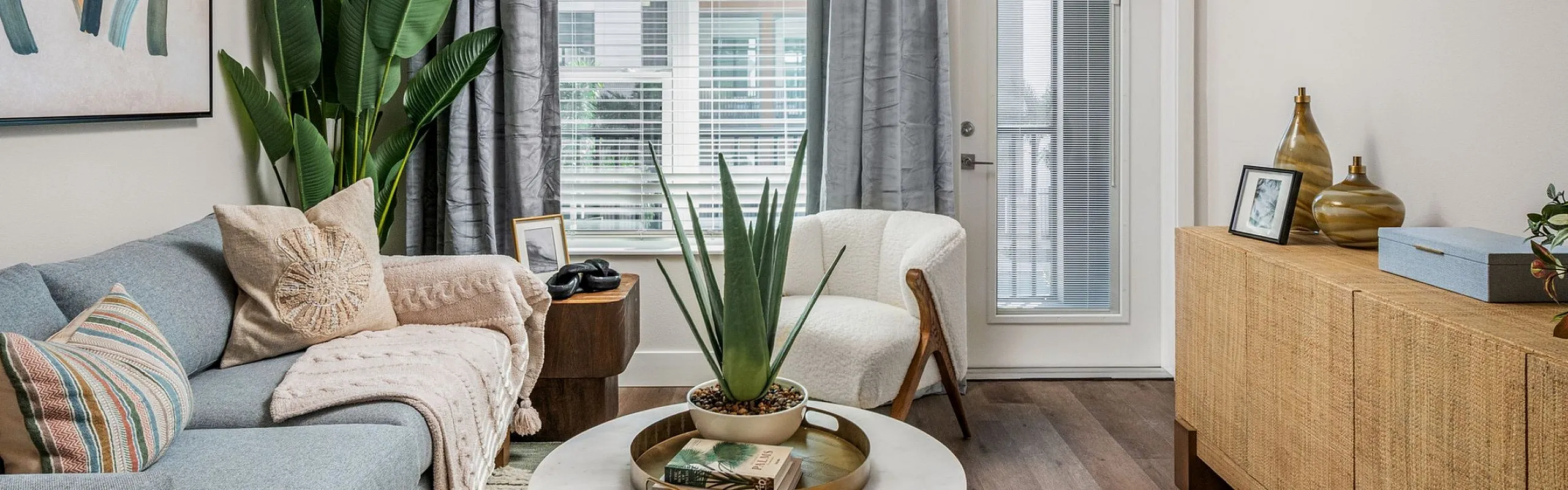 Chic living room with modern decor, featuring a cozy sofa and stylish chair, elegant artwork, and a vibrant plant accent.