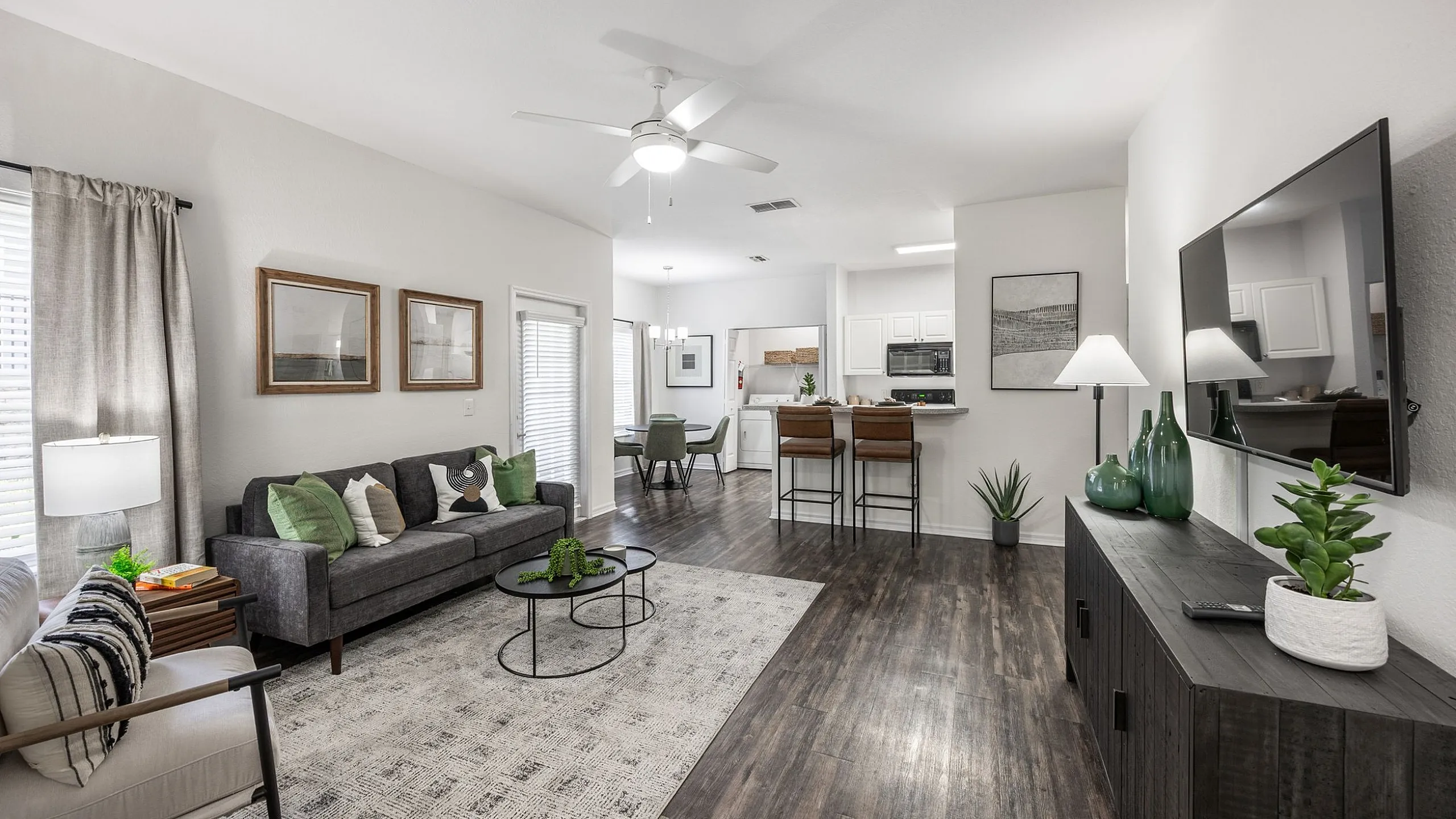 Modern open-concept living space with sleek dark wood floors, cozy seating area, and a stylish kitchen bar, perfect for contemporary living.