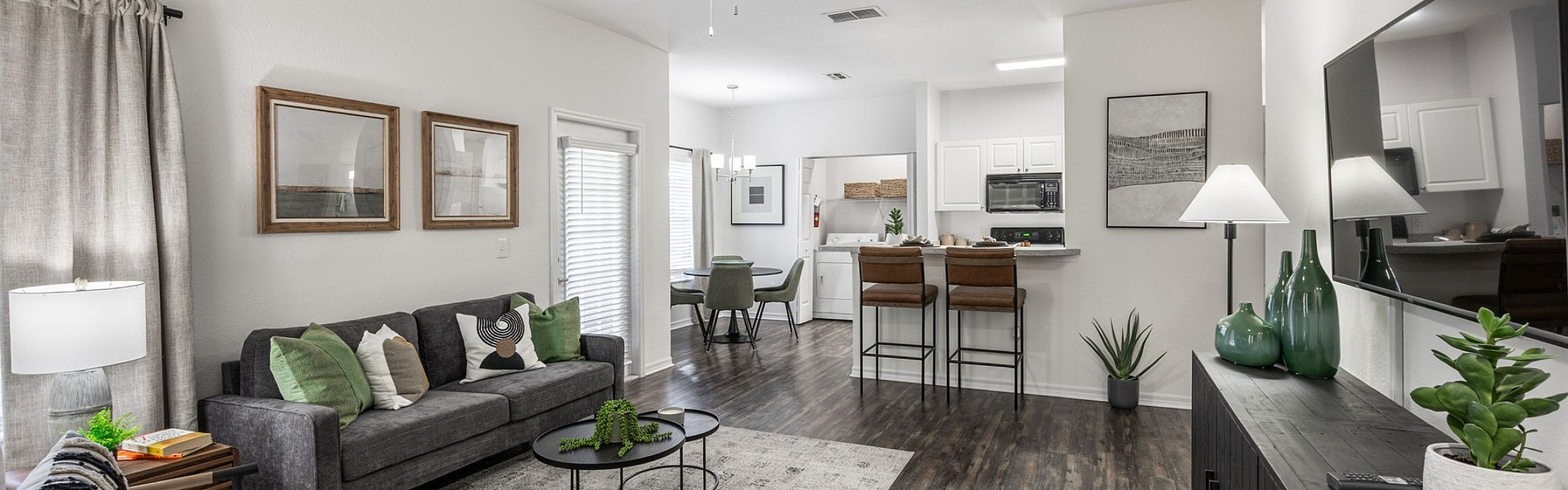 Modern open-concept living area with sleek hardwood floors, stylish decor, and spacious kitchen bar seating.