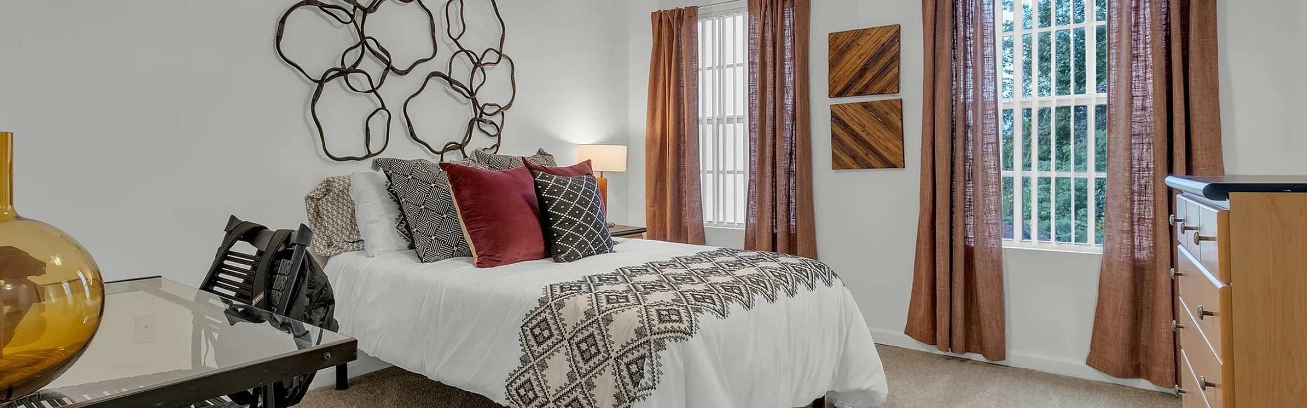 Inviting bedroom with modern decor, plush textiles, and natural light from large windows, creating a warm and cozy atmosphere.