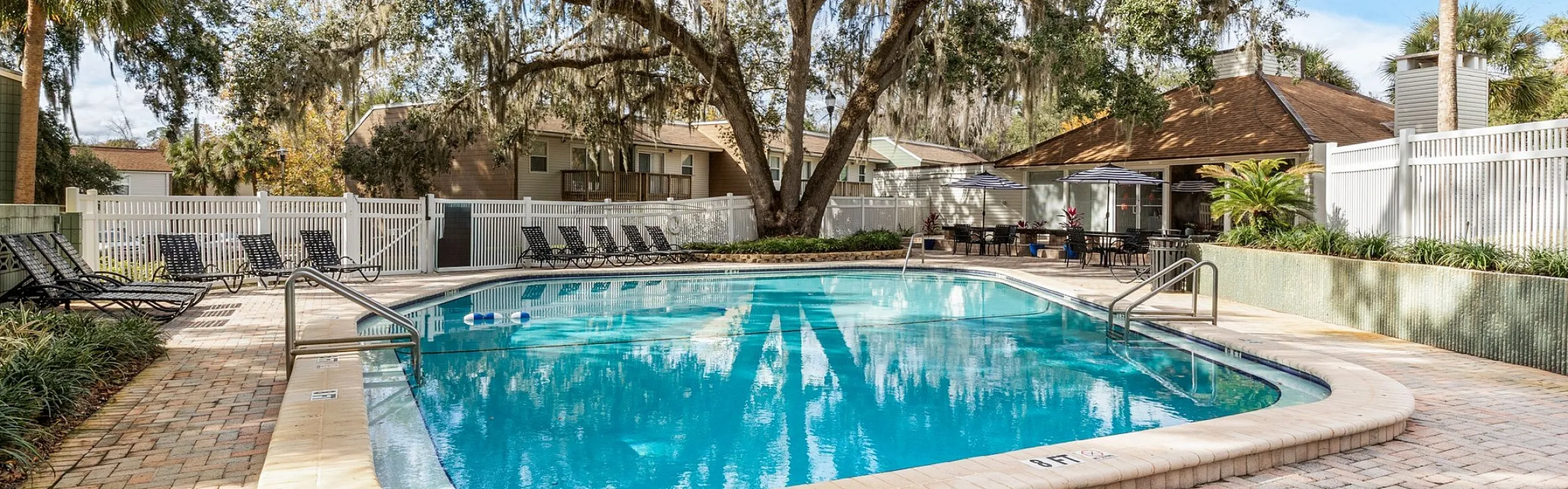 Inviting outdoor pool area surrounded by lush trees and a cozy patio, perfect for relaxation and leisure.