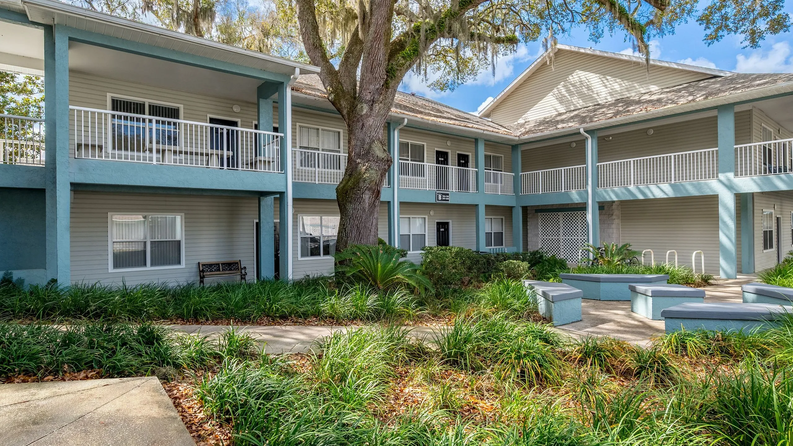 Charming apartment complex with modern two-story design, featuring beautiful balconies and surrounded by lush greenery.