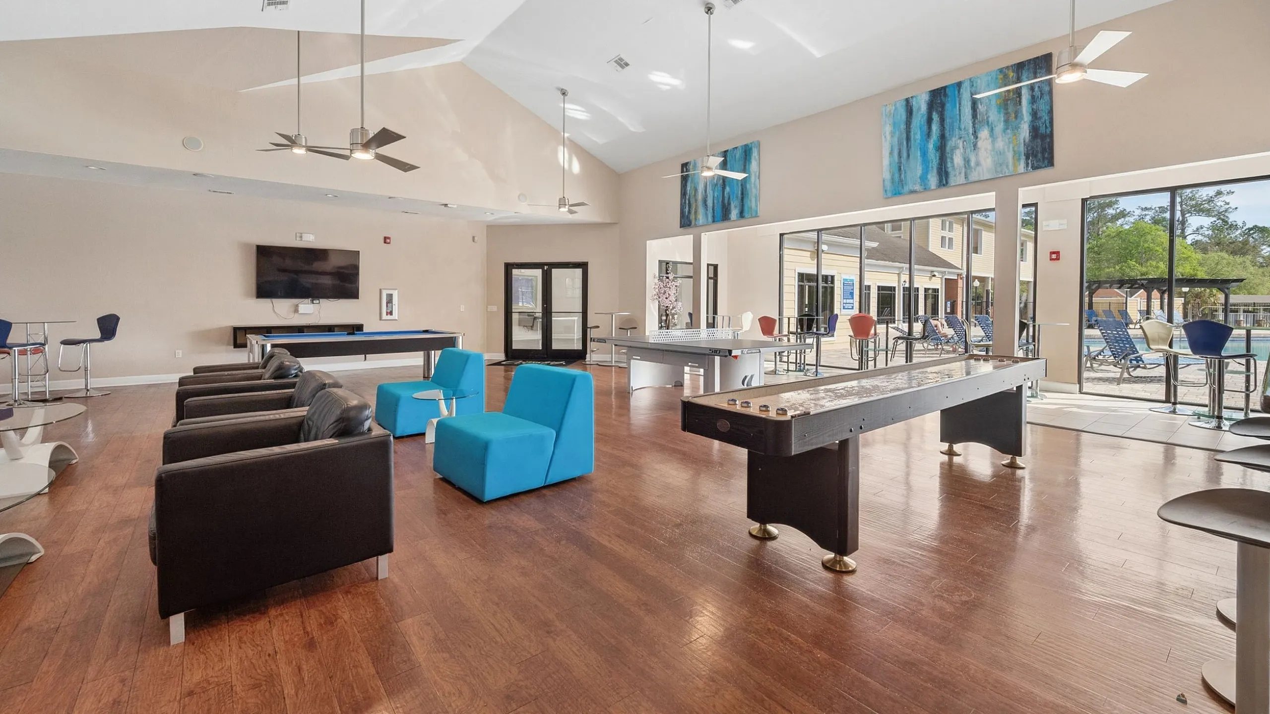 Modern community lounge with stylish furniture, ample seating, large windows, and gaming tables, offering a welcoming atmosphere.