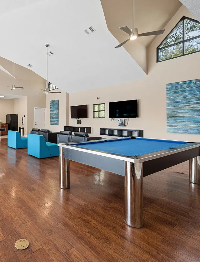Inviting recreational space featuring a sleek pool table, modern table tennis, and a cozy seating area with stylish decor and polished wood floors.
