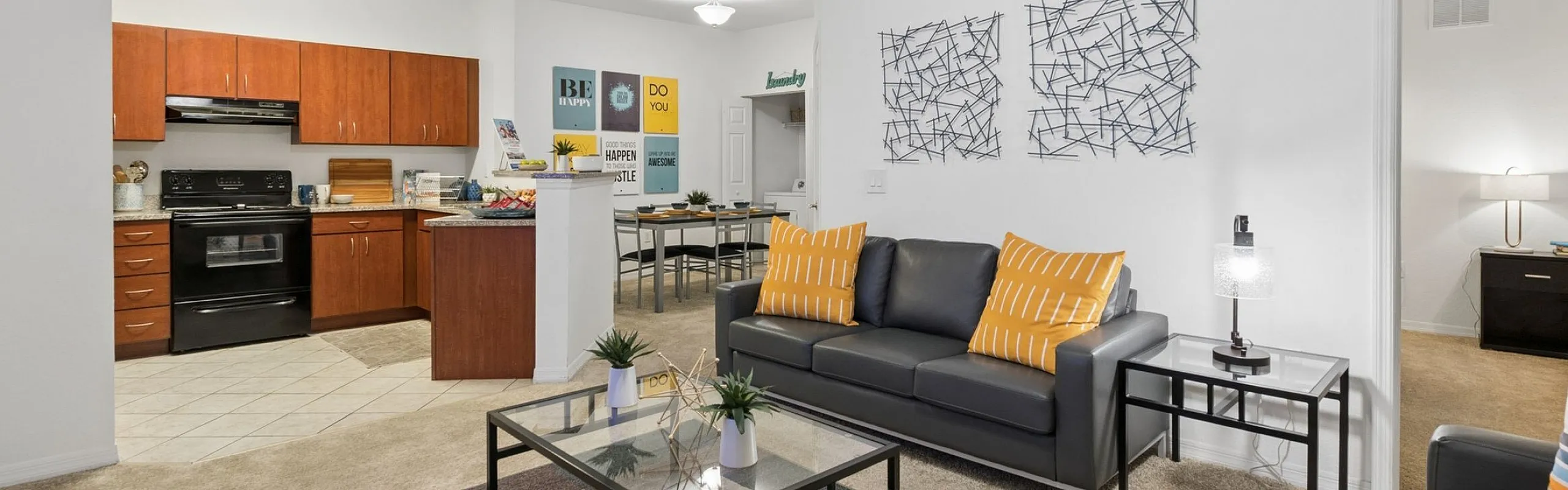 Contemporary open-plan living room and kitchen with stylish furnishing, featuring cozy seating, modern artwork, and a spacious layout.