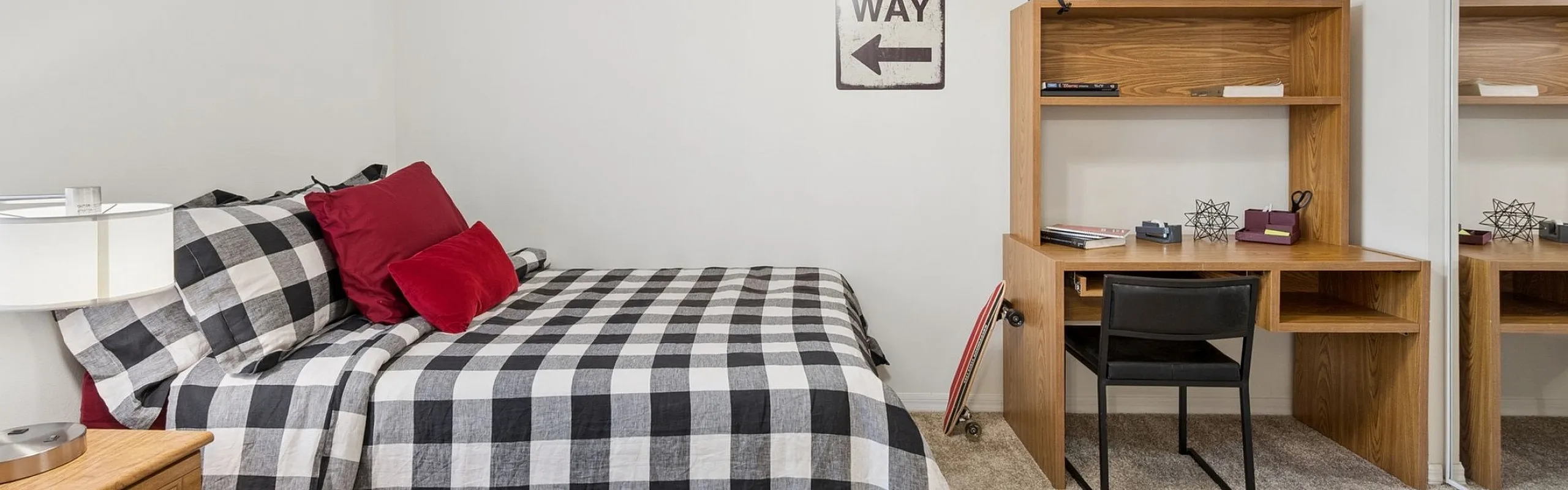 Inviting bedroom with stylish plaid bedding, cozy carpeted floor, and functional wooden desk space.