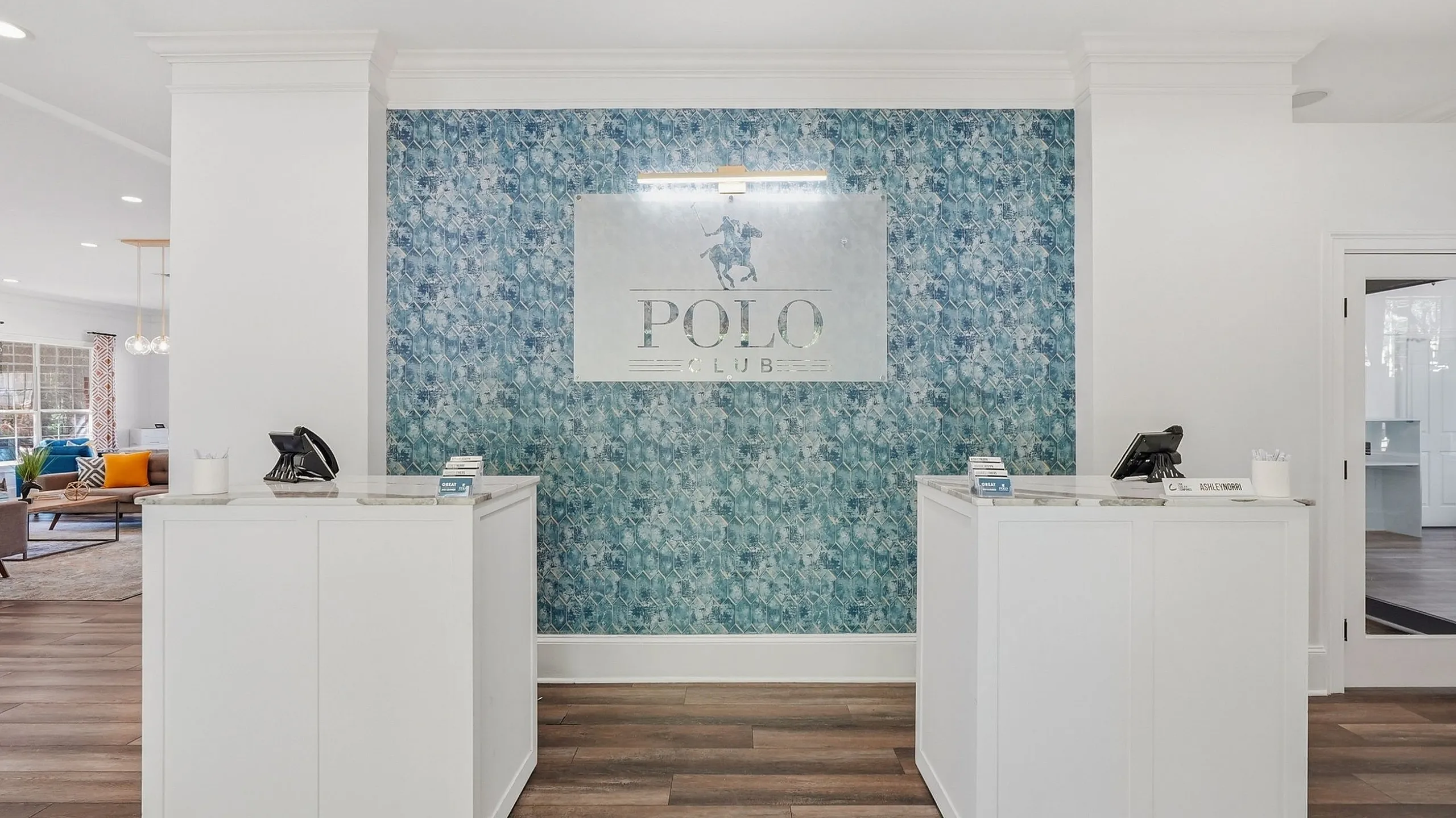 Elegant apartment lobby featuring a stylish reception area, highlighted by a blue textured accent wall and modern white desks.