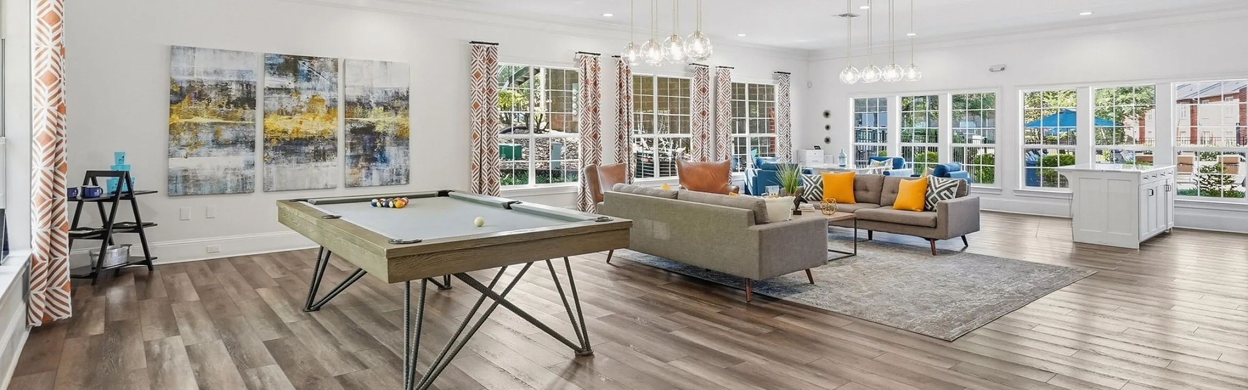 Spacious, elegant living area with modern decor, showcasing a cozy sitting zone, vibrant artwork, and a stylish pool table under chic lighting.