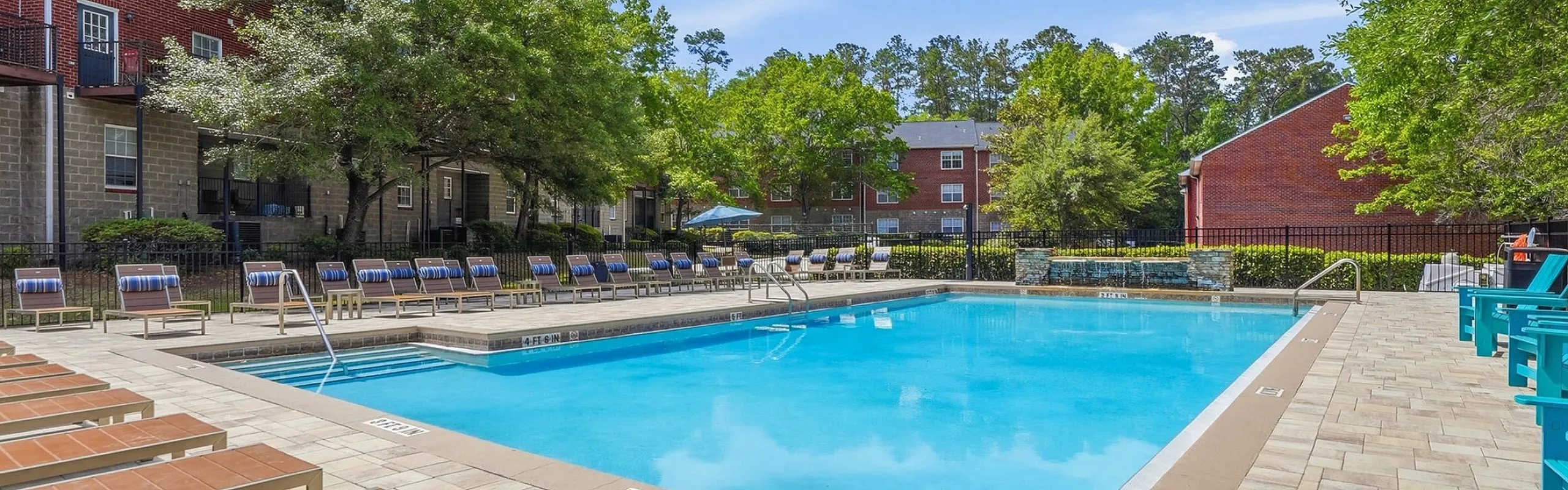 Inviting outdoor pool area with stylish lounge chairs and lush green surroundings, perfect for relaxation and leisure.