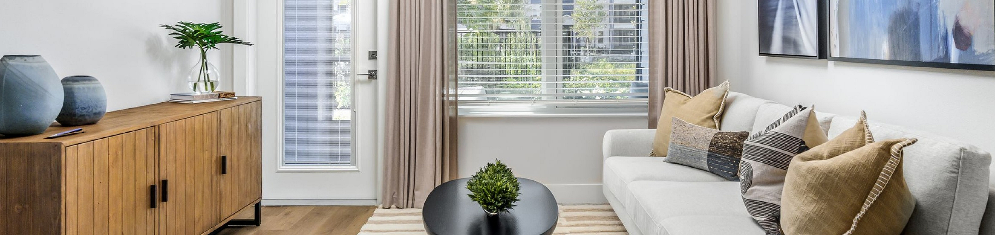 Bright, contemporary living room featuring elegant artwork, a plush sofa, and a stylish wooden sideboard, offering a perfect blend of comfort and modern design.