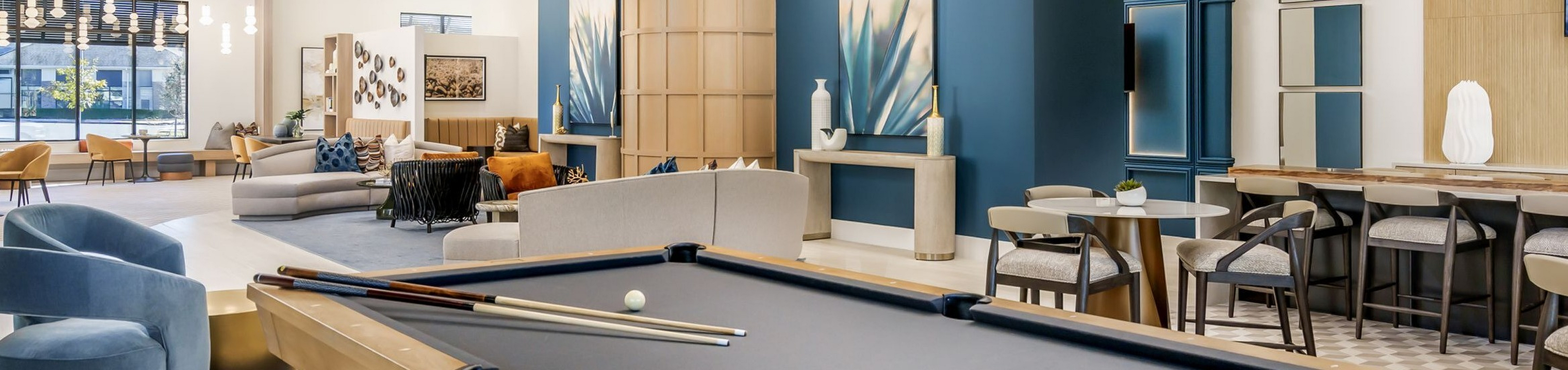 Luxurious modern lounge with a sleek pool table, stylish seating, and artistic decor, offering an inviting space for relaxation and entertainment.