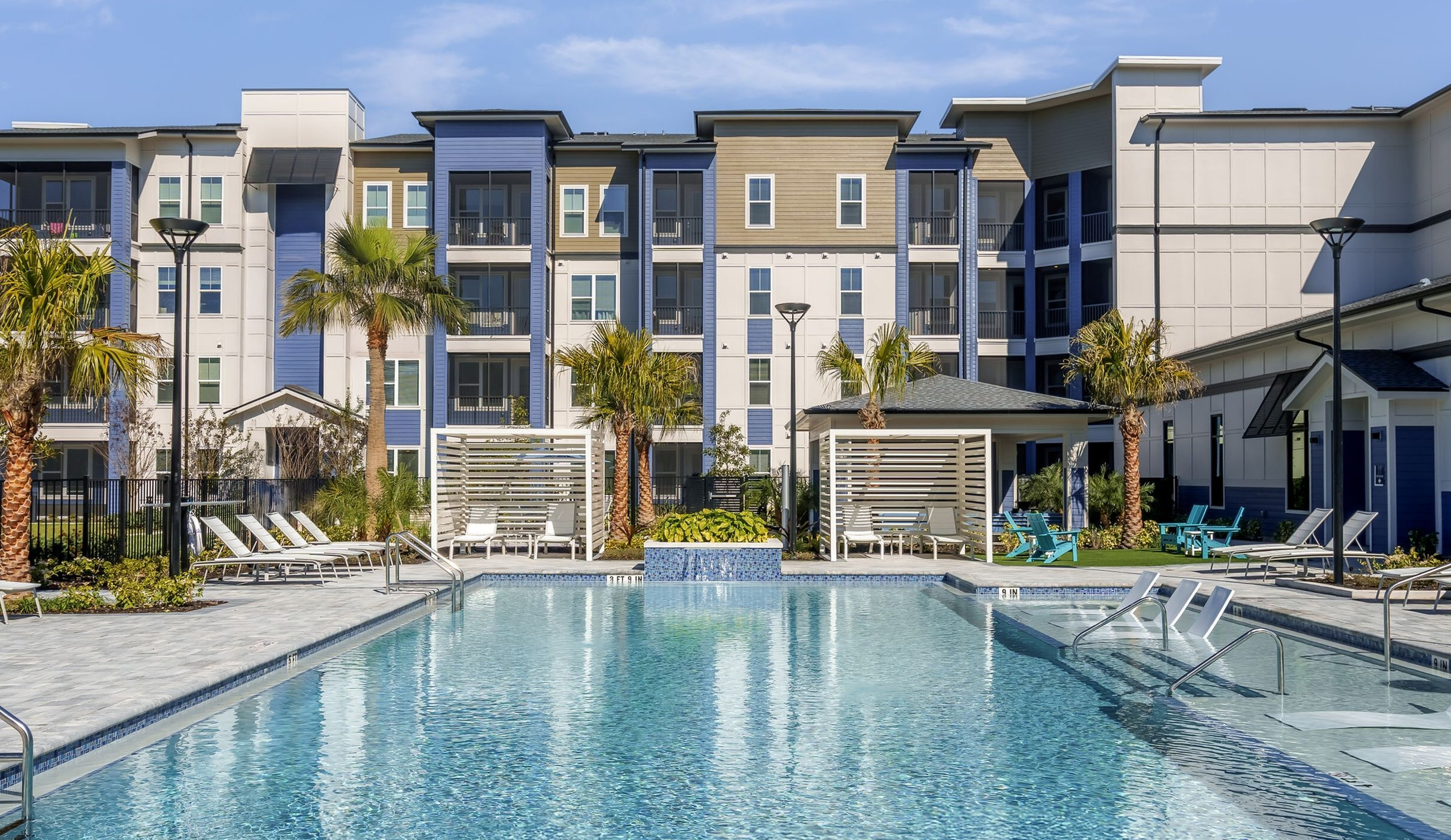 Luxurious apartment complex with a sparkling swimming pool, modern architecture, and lush palm trees, perfect for relaxation and leisure.