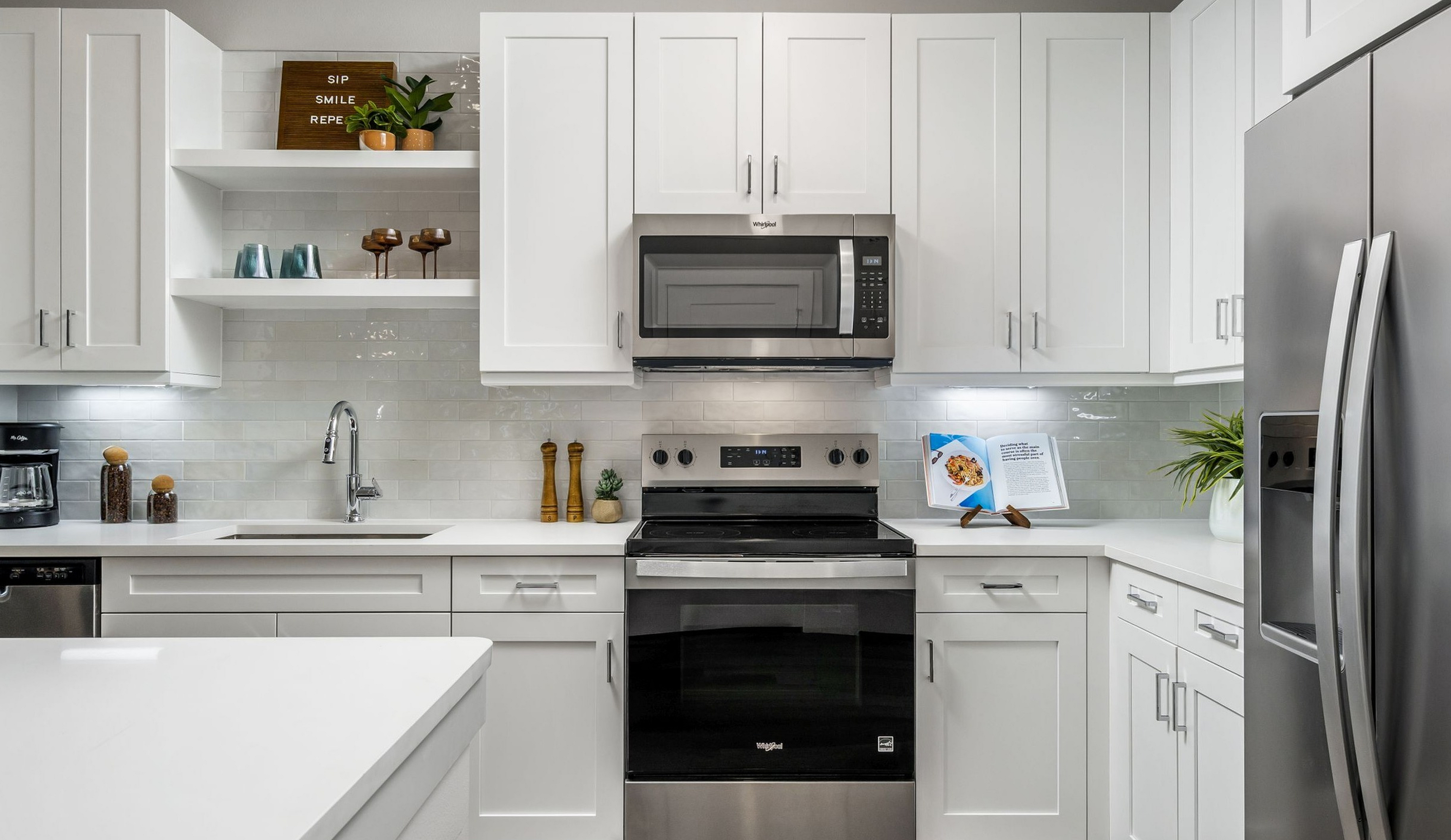 Sleek modern kitchen with white cabinetry, stainless steel appliances, and stylish decor accents.